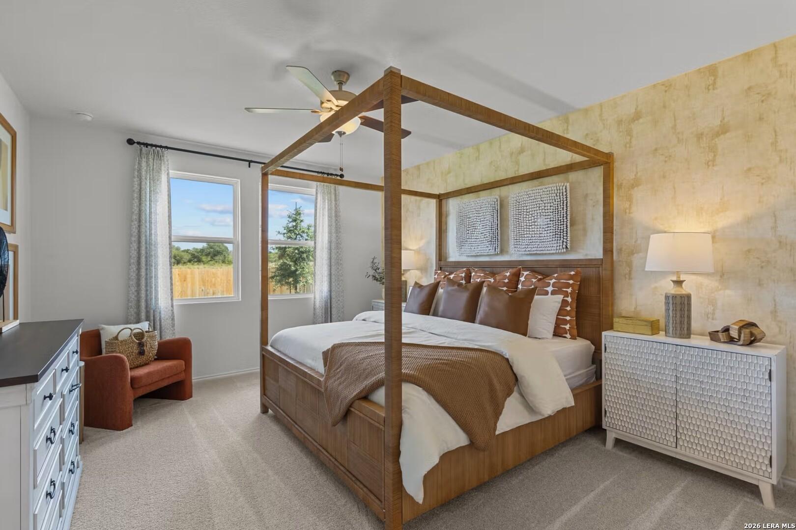 Elegant master bedroom with wooden four-poster bed, orange pillows, textured walls, and window overlooking backyard in Davidson Homes The Daphne K, Bricewood San Antonio