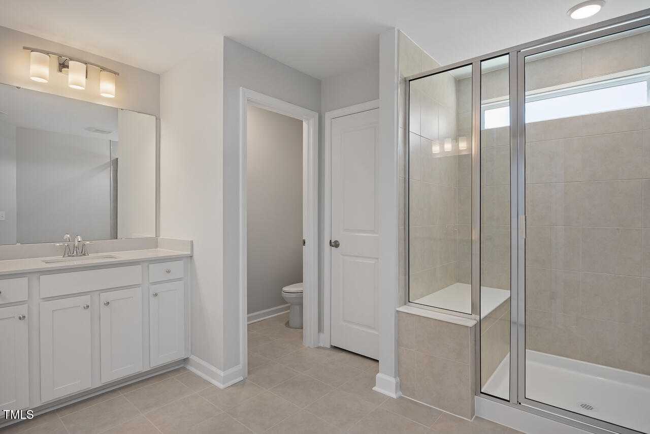 Modern master bathroom with double vanity, frameless glass shower, and bench seat in Davidson Homes The Graham, Fuquay-Varina, NC