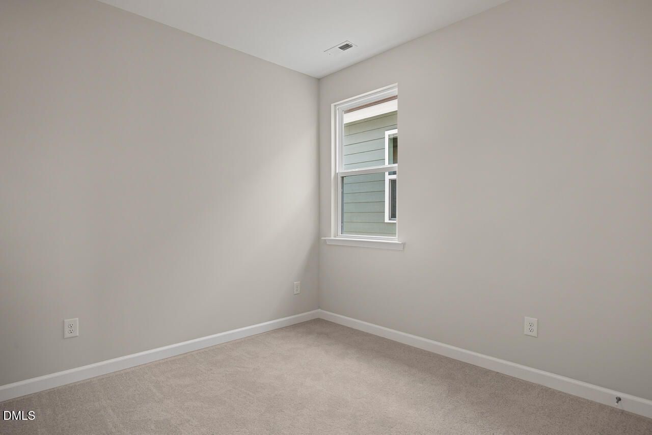 Bright, carpeted bedroom with neutral walls in The Alexander C floor plan by Davidson Homes, Forestville Yard, Knightdale, NC.