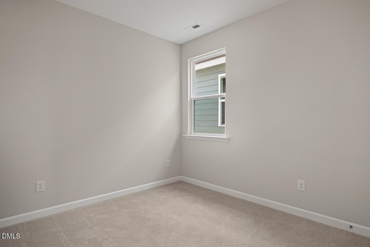 Bright, carpeted bedroom with neutral walls in The Alexander C floor plan by Davidson Homes, Forestville Yard, Knightdale, NC.