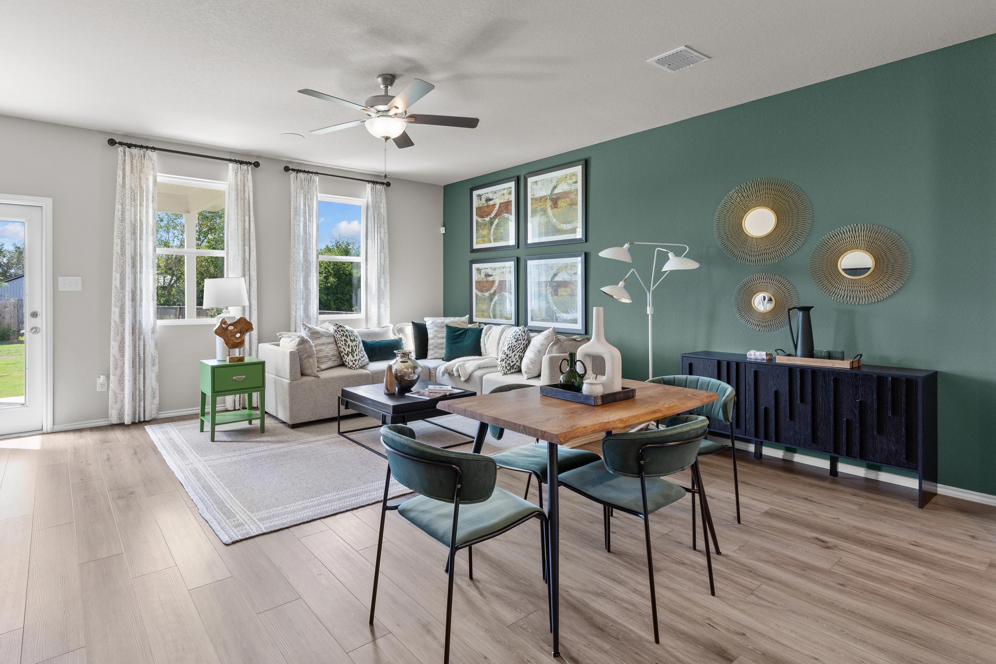 Spacious open-concept living and dining room at Comanche Ridge in San Antonio TX with emerald green accent wall, hardwood floors, and modern furniture