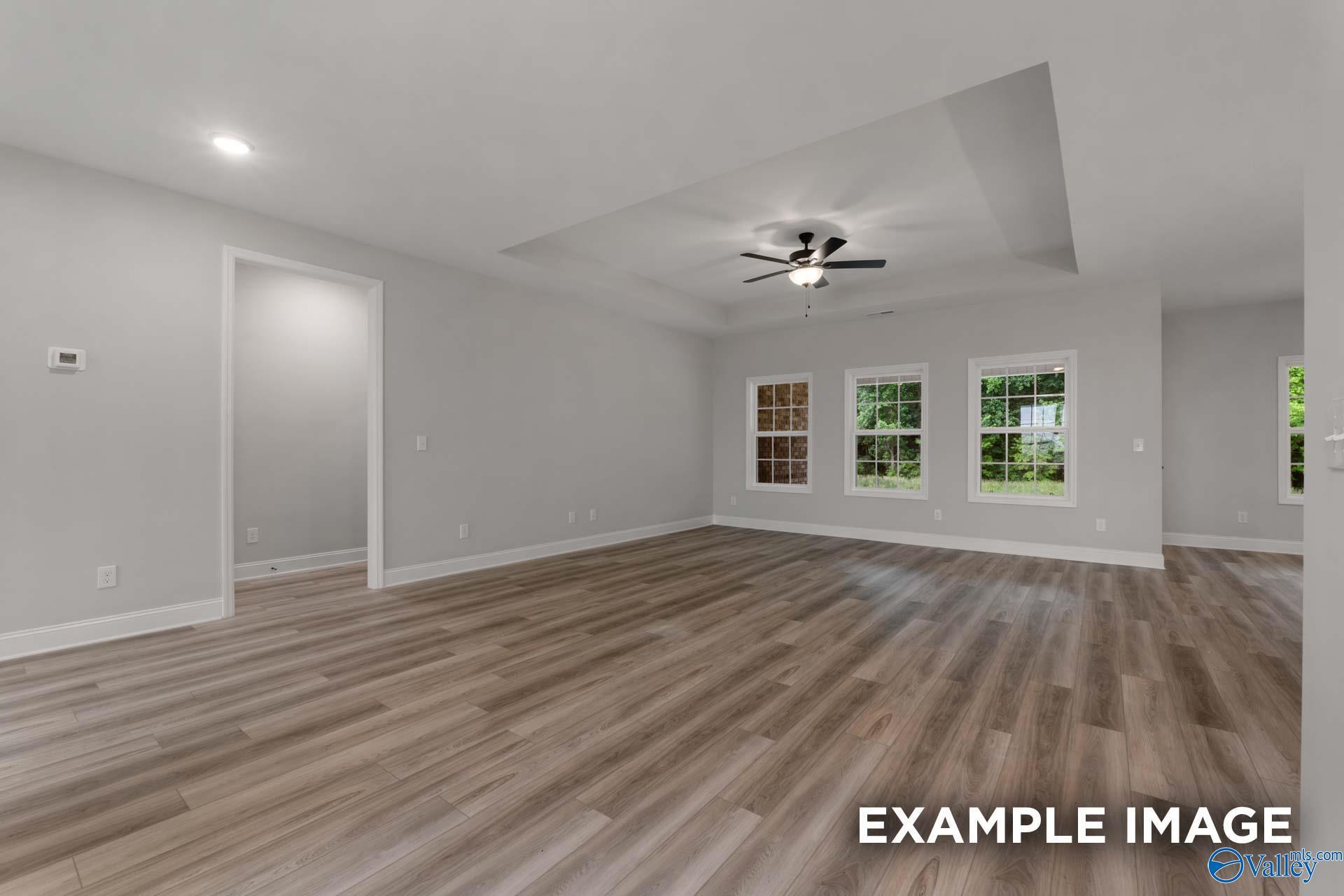 Bright living room with hardwood floors, large windows, and ceiling fan in Davidson Homes The Finleigh, Meridianville, Alabama