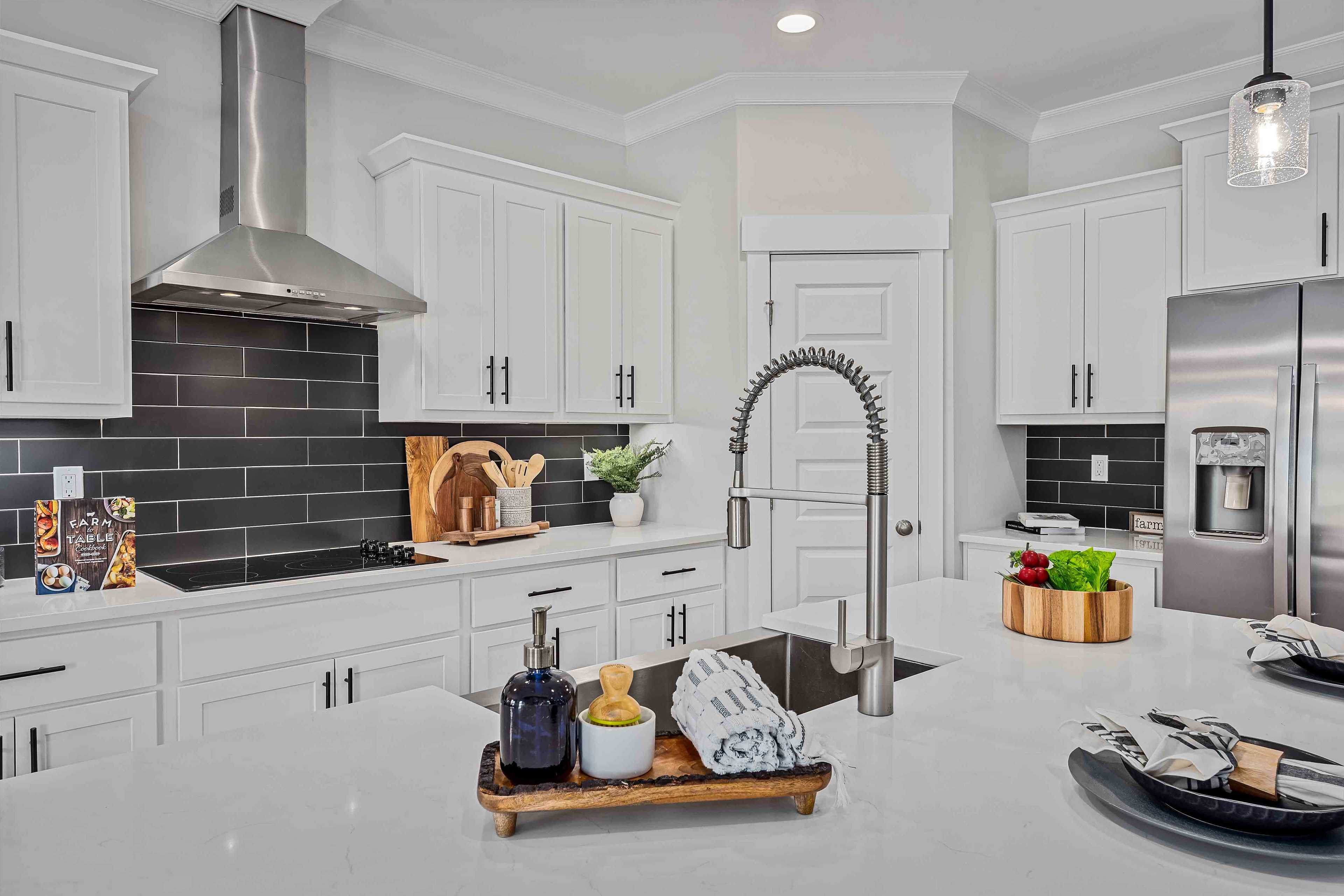 Spacious white kitchen in Cain Park Hartselle Alabama with shaker cabinets black subway tile backsplash quartz counters stainless appliances