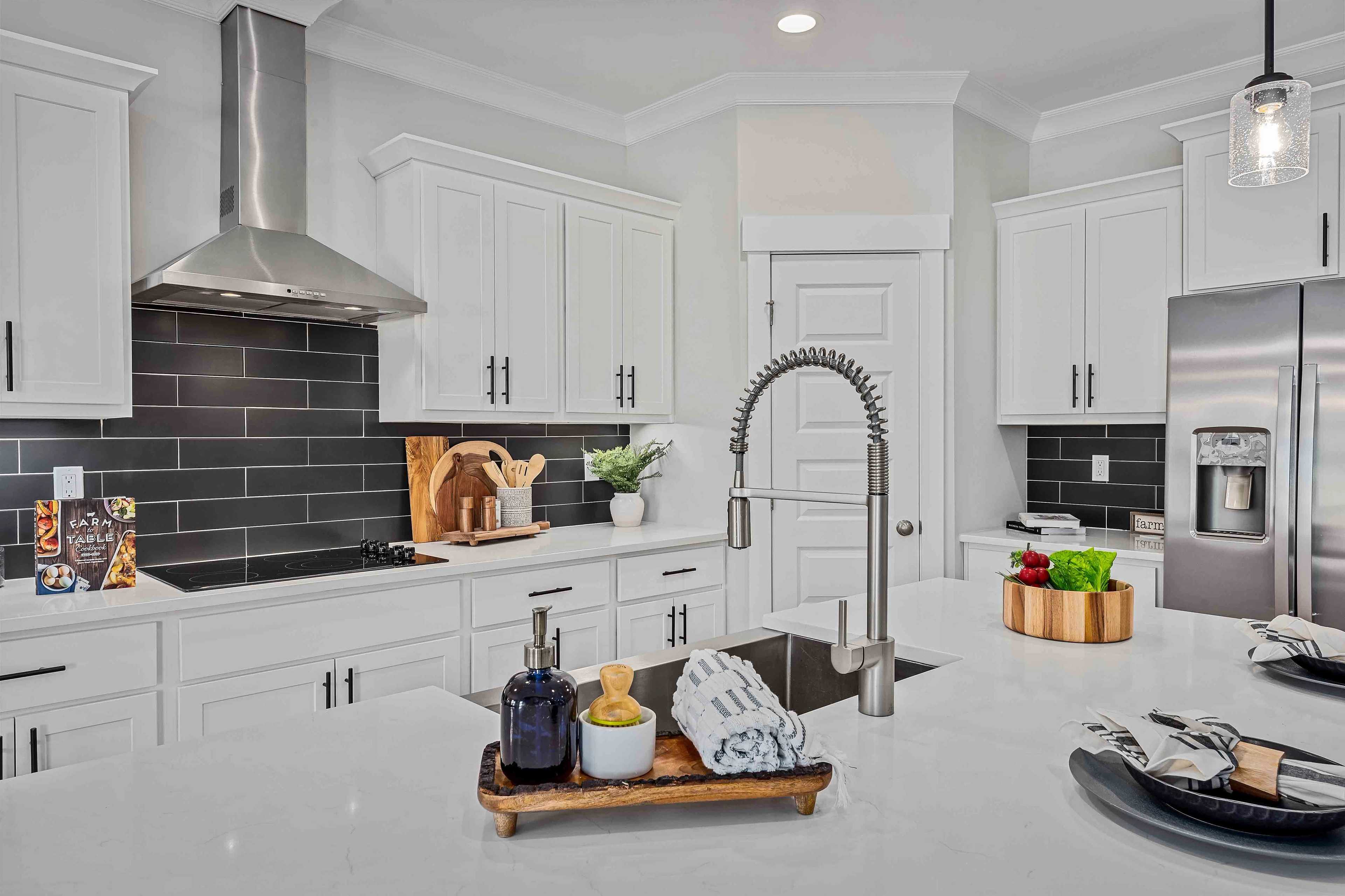 Spacious white kitchen in Cain Park Hartselle Alabama with shaker cabinets black subway tile backsplash quartz counters stainless appliances