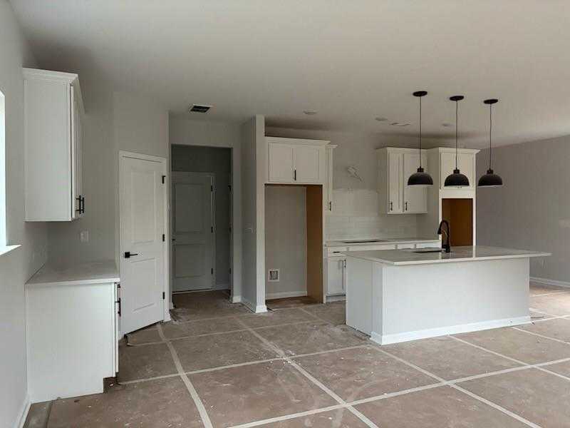 Spacious unfinished kitchen with white shaker cabinets, quartz island, pendant lights in Davidson Homes The Rabun C, Winder GA