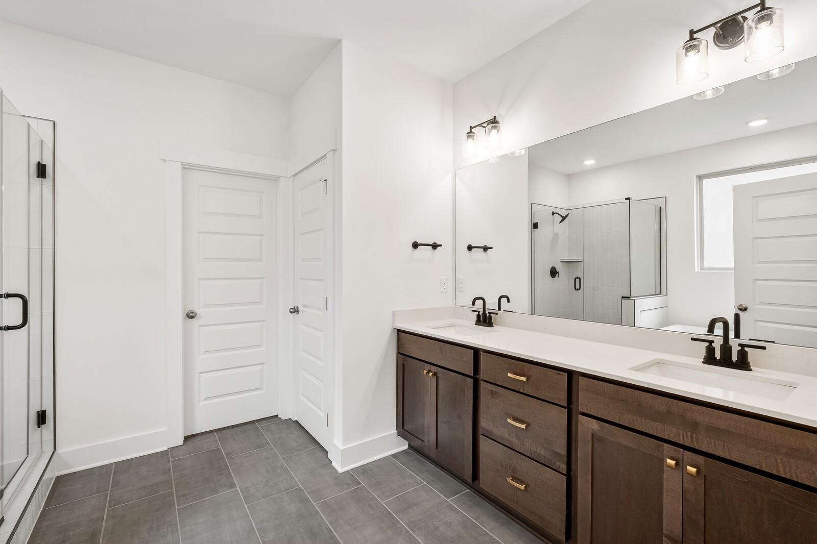 Modern master bathroom with double wood vanity, white quartz counters, glass shower in Davidson Homes Ridgeport C, Gallatin, TN