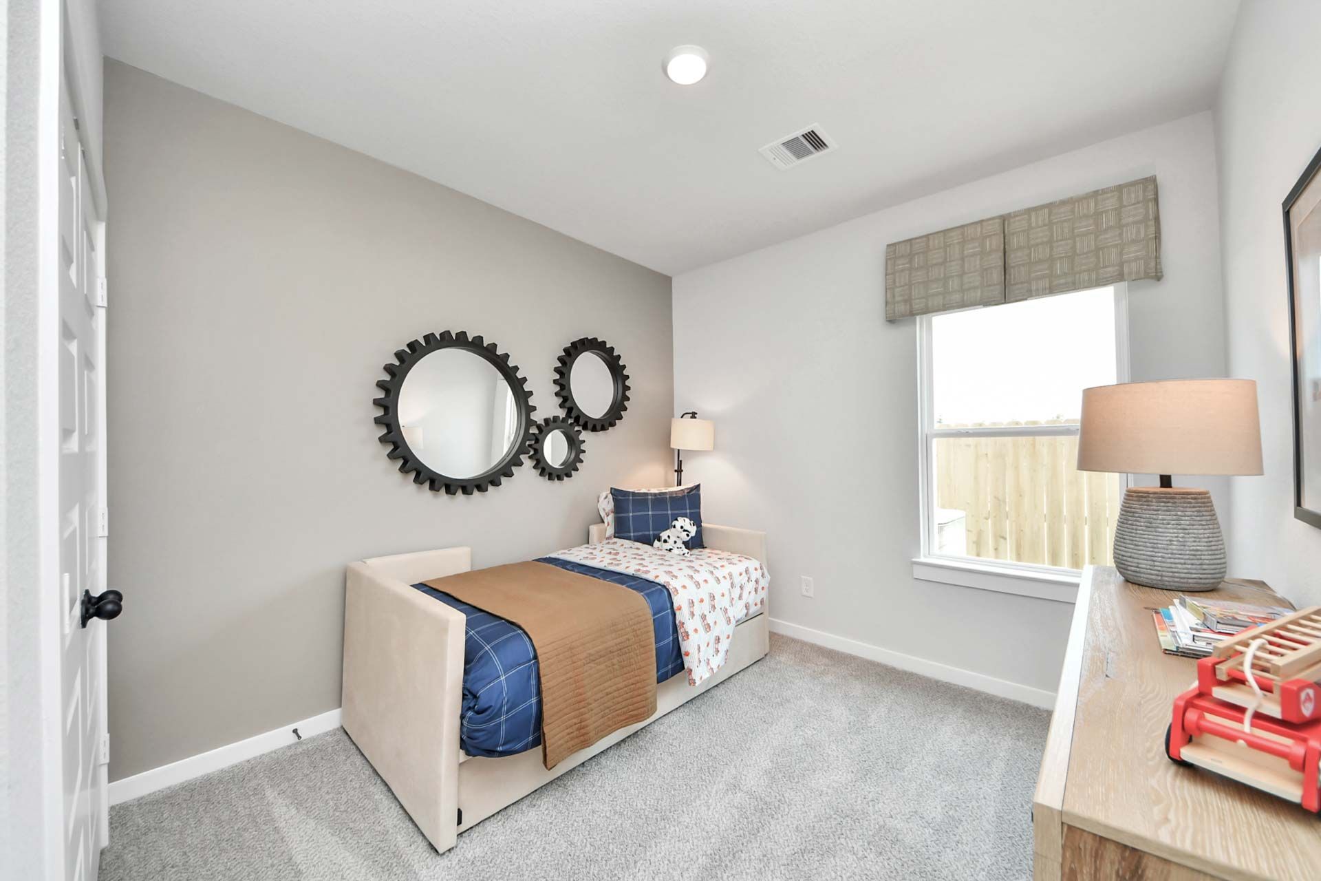 Cozy bedroom with twin daybed and gear-shaped wall decor at Enclave at Newport in Crosby, Texas by Davidson Homes.