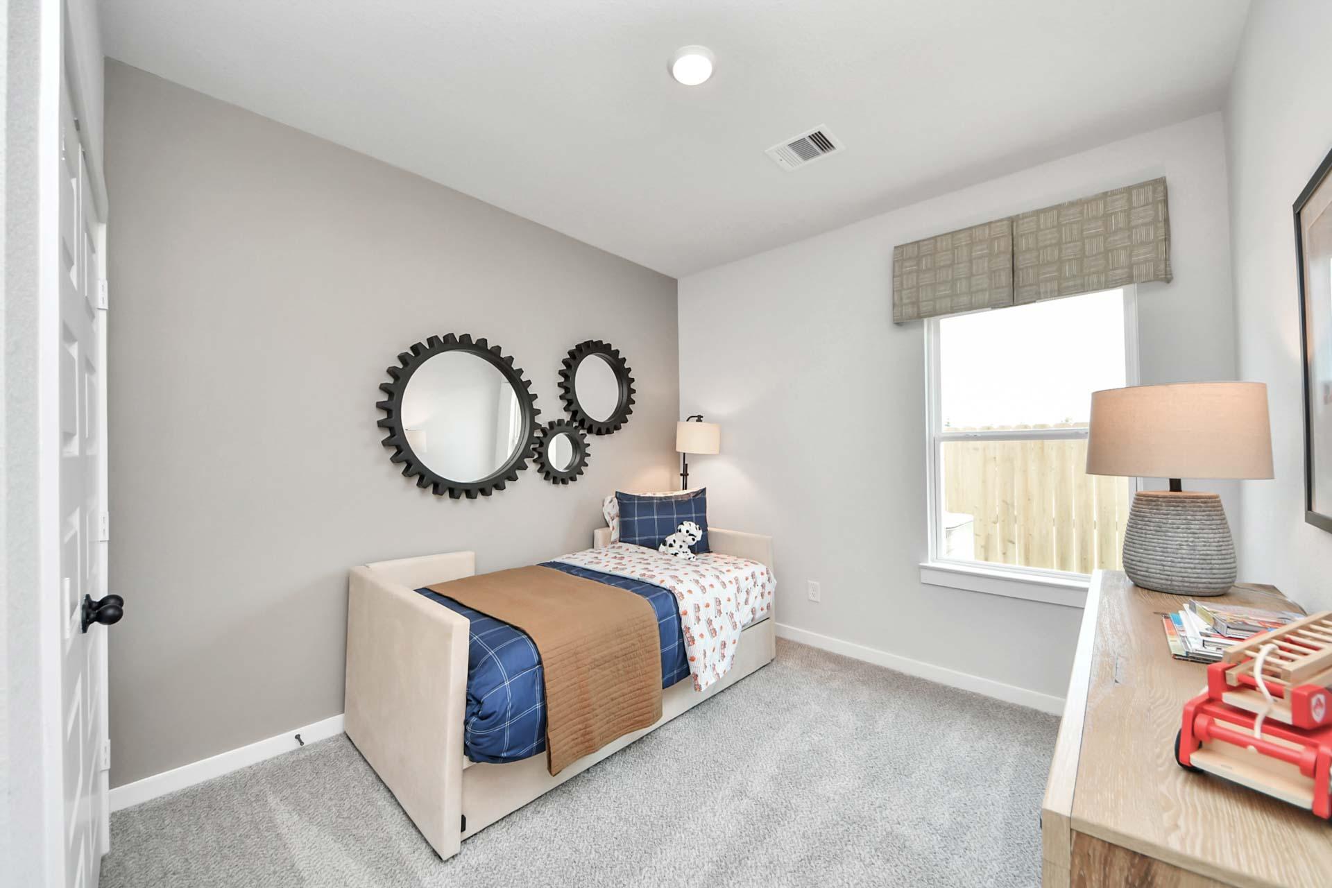 Cozy bedroom with twin daybed and gear-shaped wall decor at Enclave at Newport in Crosby, Texas by Davidson Homes.