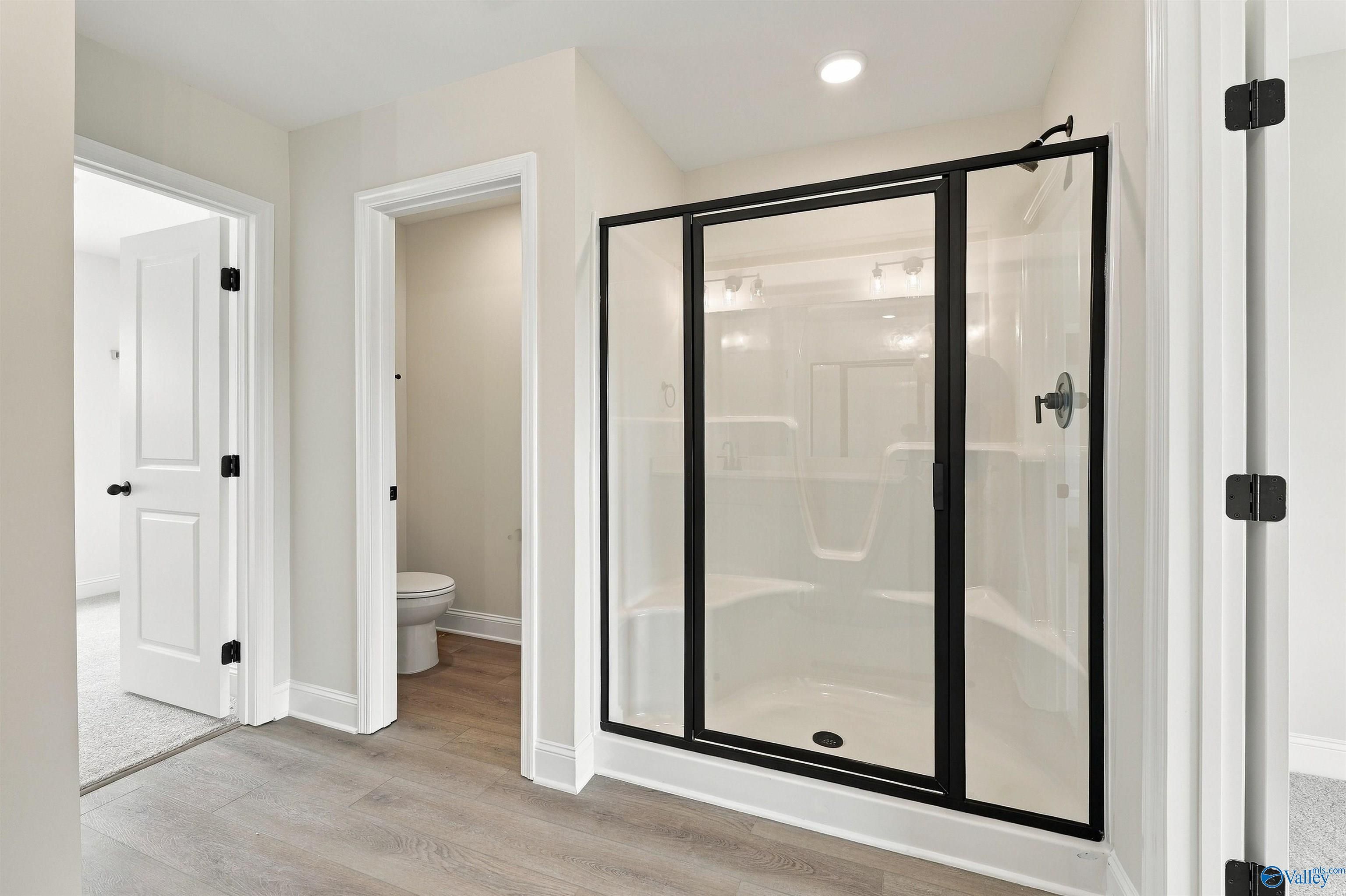 Corner walk-in shower with black frame in primary bathroom of Davidson Homes The Shelby A, Athens, Alabama