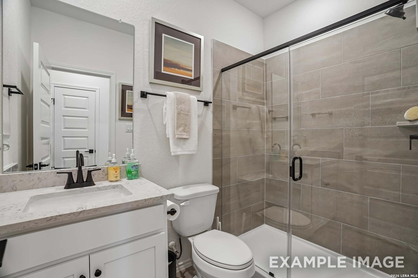 Modern bathroom with glass shower, white vanity and marble countertop in Davidson Homes Pinecrest F plan, San Antonio, TX