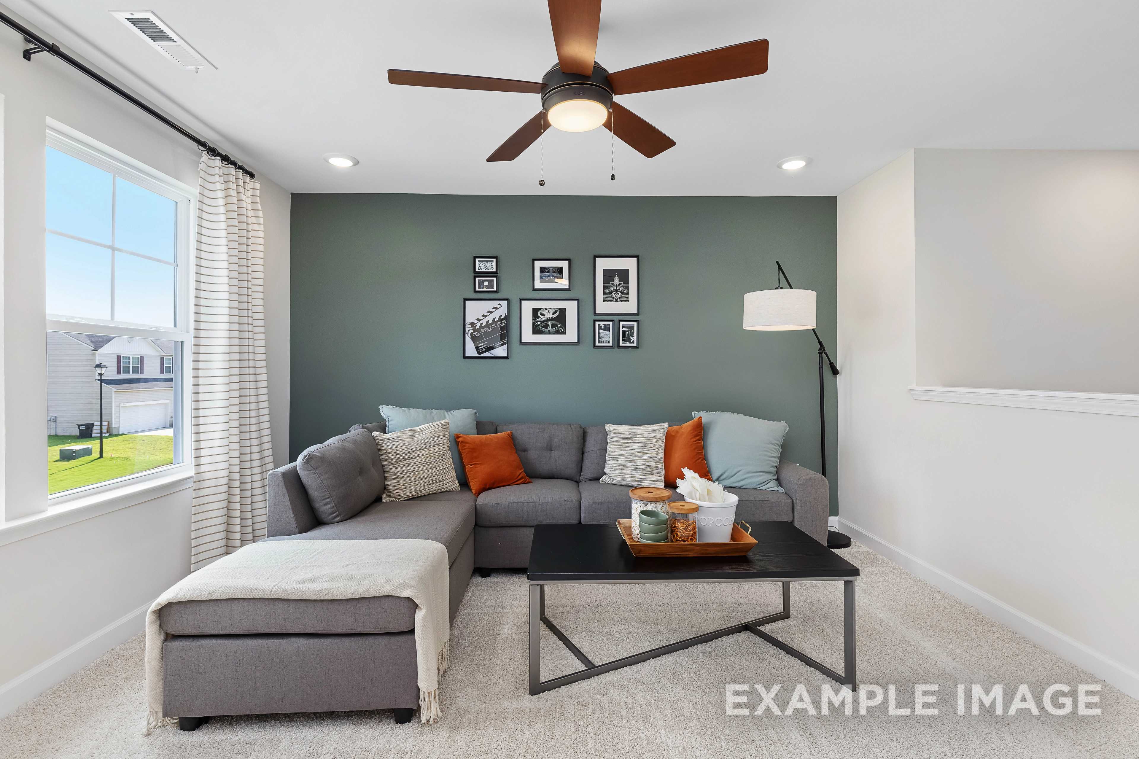 Cozy living room in The Willow B home design by Davidson Homes, gray L-shaped sofa, orange pillows, ceiling fan