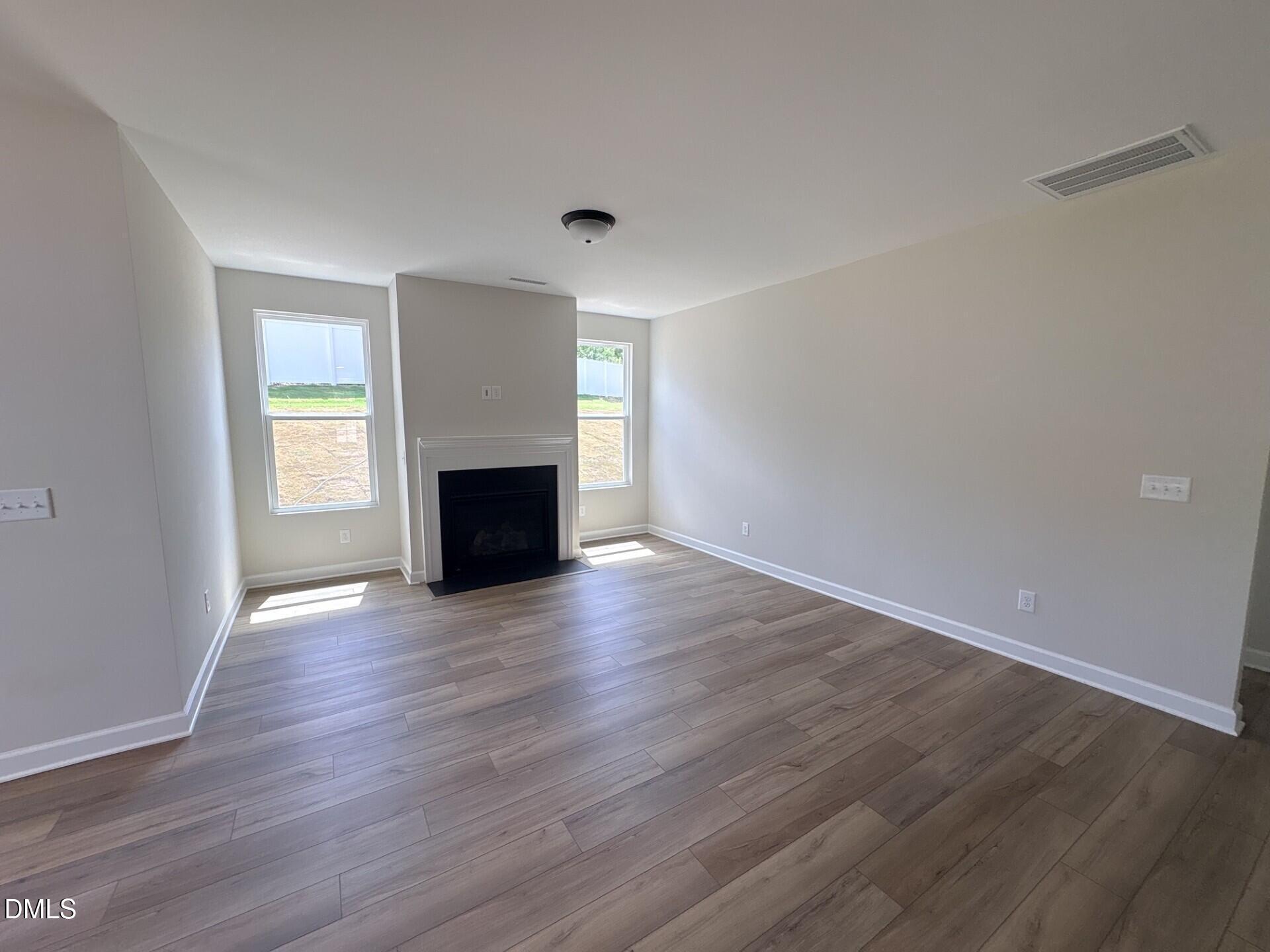 Spacious living room with fireplace and wood-style flooring in The Ash C floor plan at Woodland Crossing, Zebulon, NC.