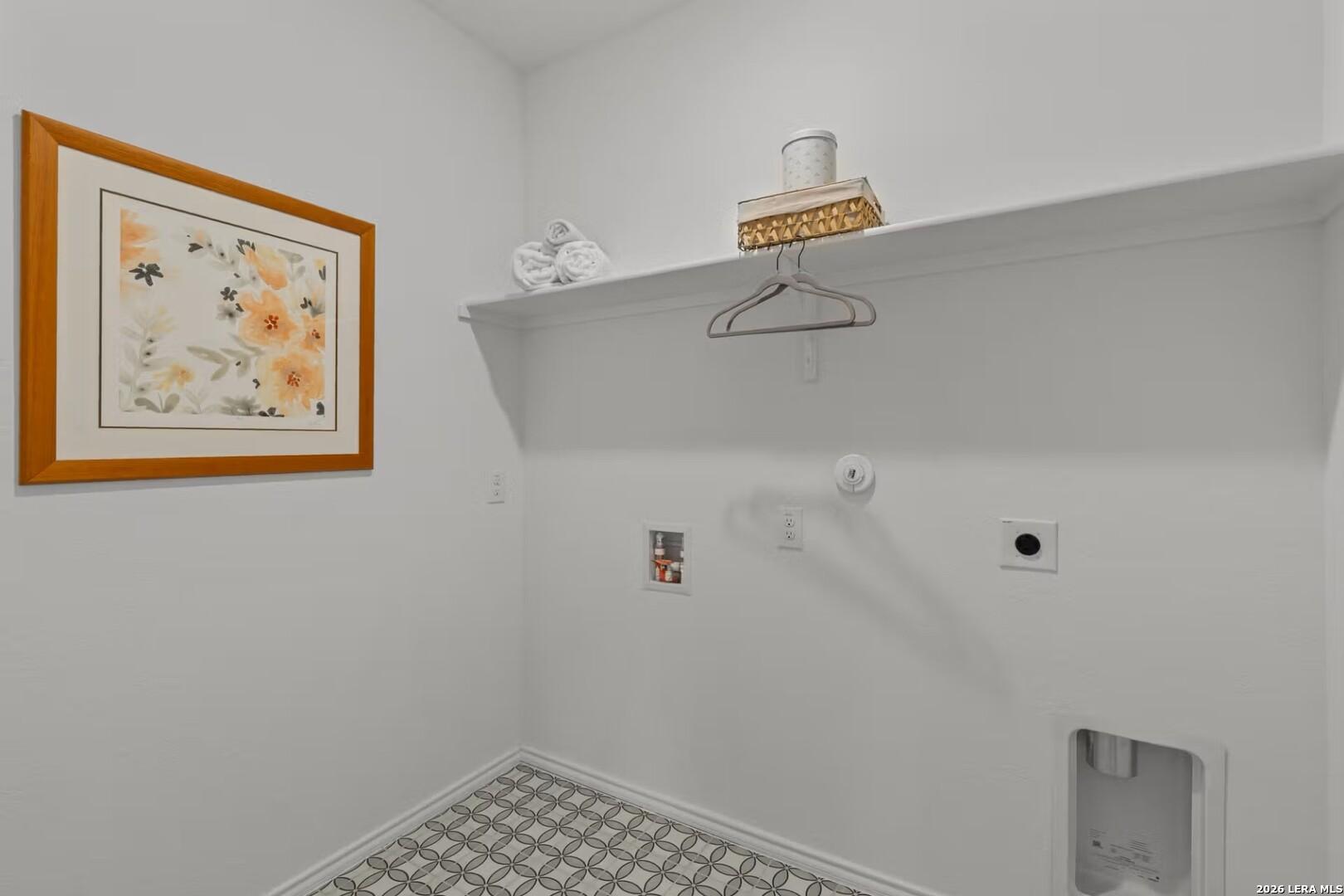 Bright laundry room with white shelves, folded towels, floral artwork, and utility hookups in The Daphne K, Bricewood, San Antonio