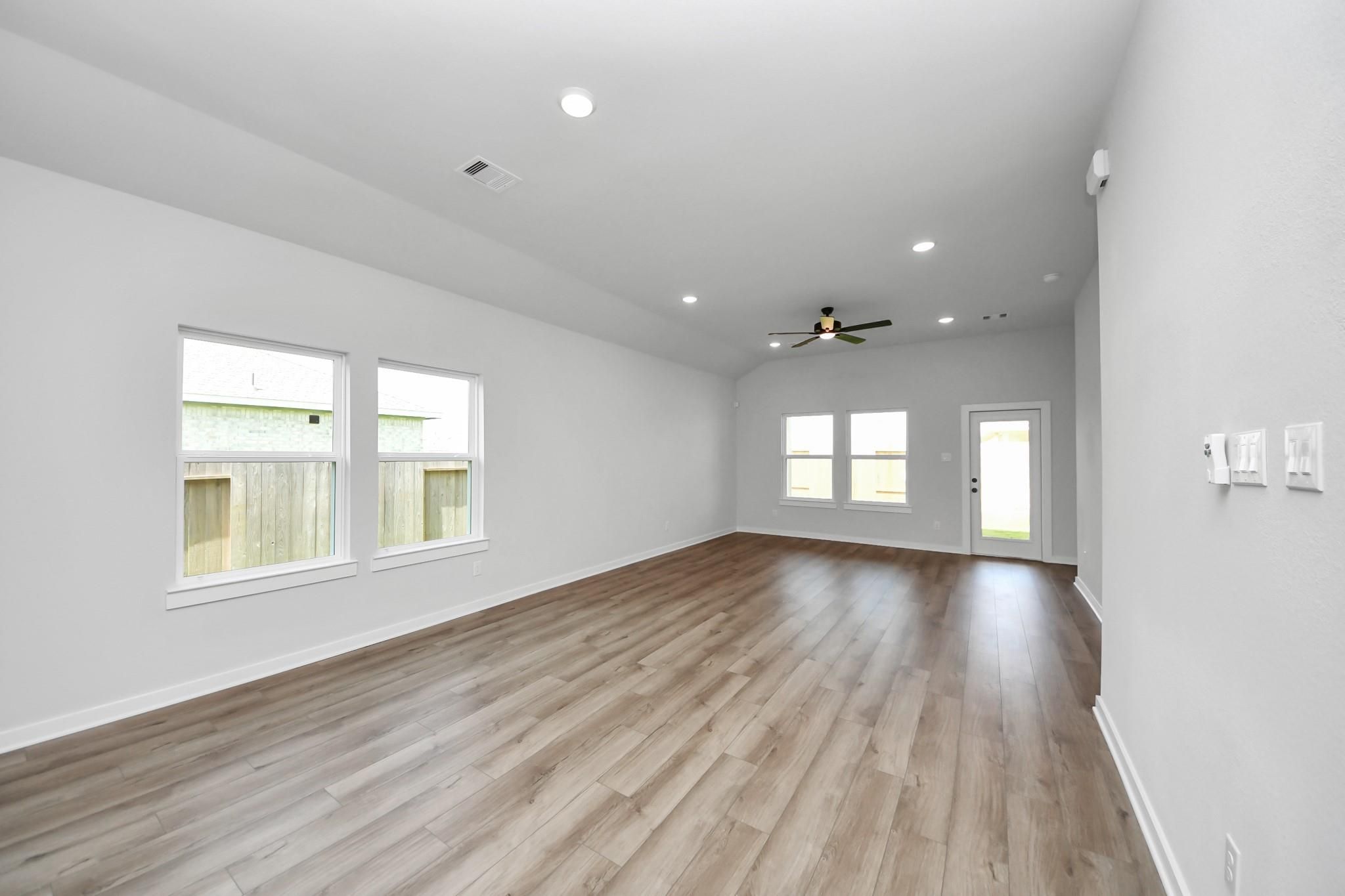 Spacious, open-concept living room with wood-look flooring in The Riviera C floor plan, River Ranch Meadows, Dayton, Texas.