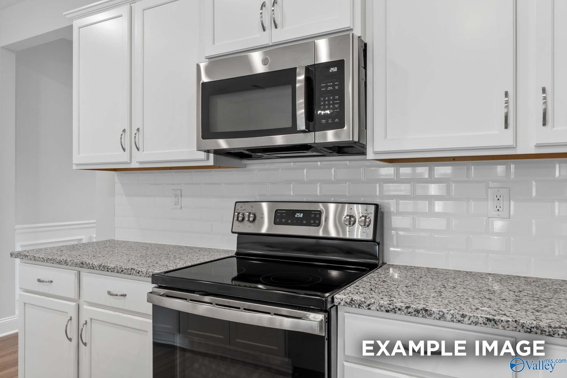 Modern kitchen featuring white cabinets, granite countertops, stainless steel microwave and range in Davidson Homes The Cumberland D, Decatur, Alabama