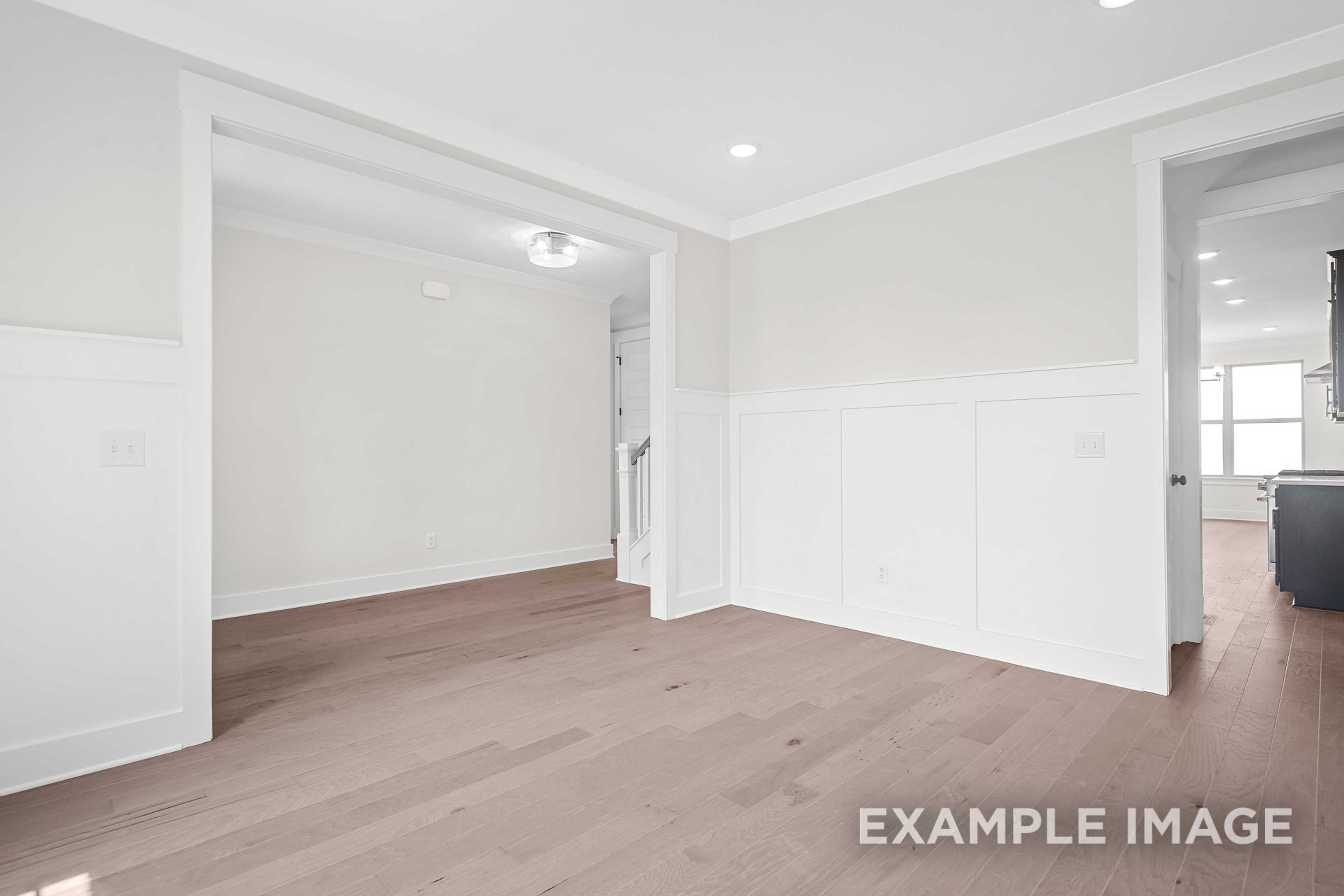 Spacious foyer in The Hawkins two-story home with white wainscoting, open archways, staircase, and hardwood floors