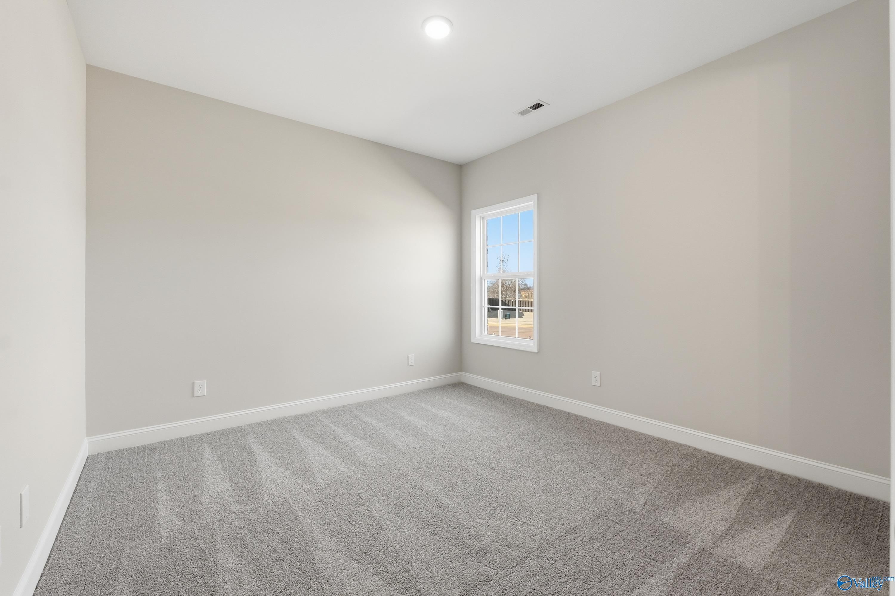 Bright secondary bedroom with gray walls, carpet, and large window in The Finleigh 3-bedroom home, Harvest, Alabama