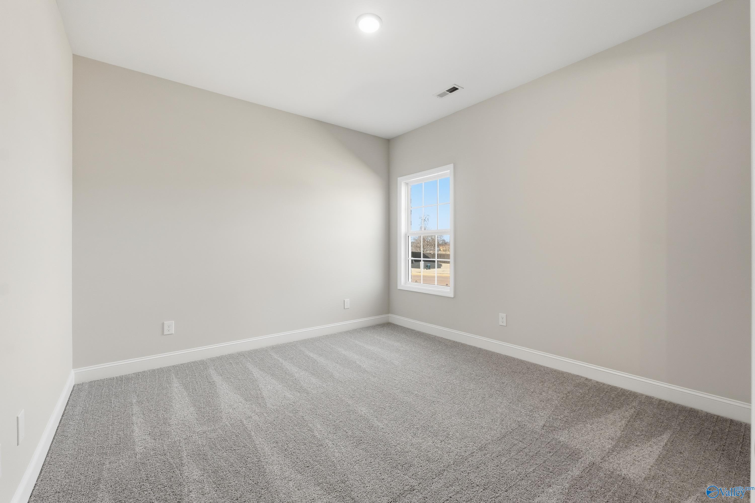 Bright secondary bedroom with gray walls, carpet, and large window in The Finleigh 3-bedroom home, Harvest, Alabama