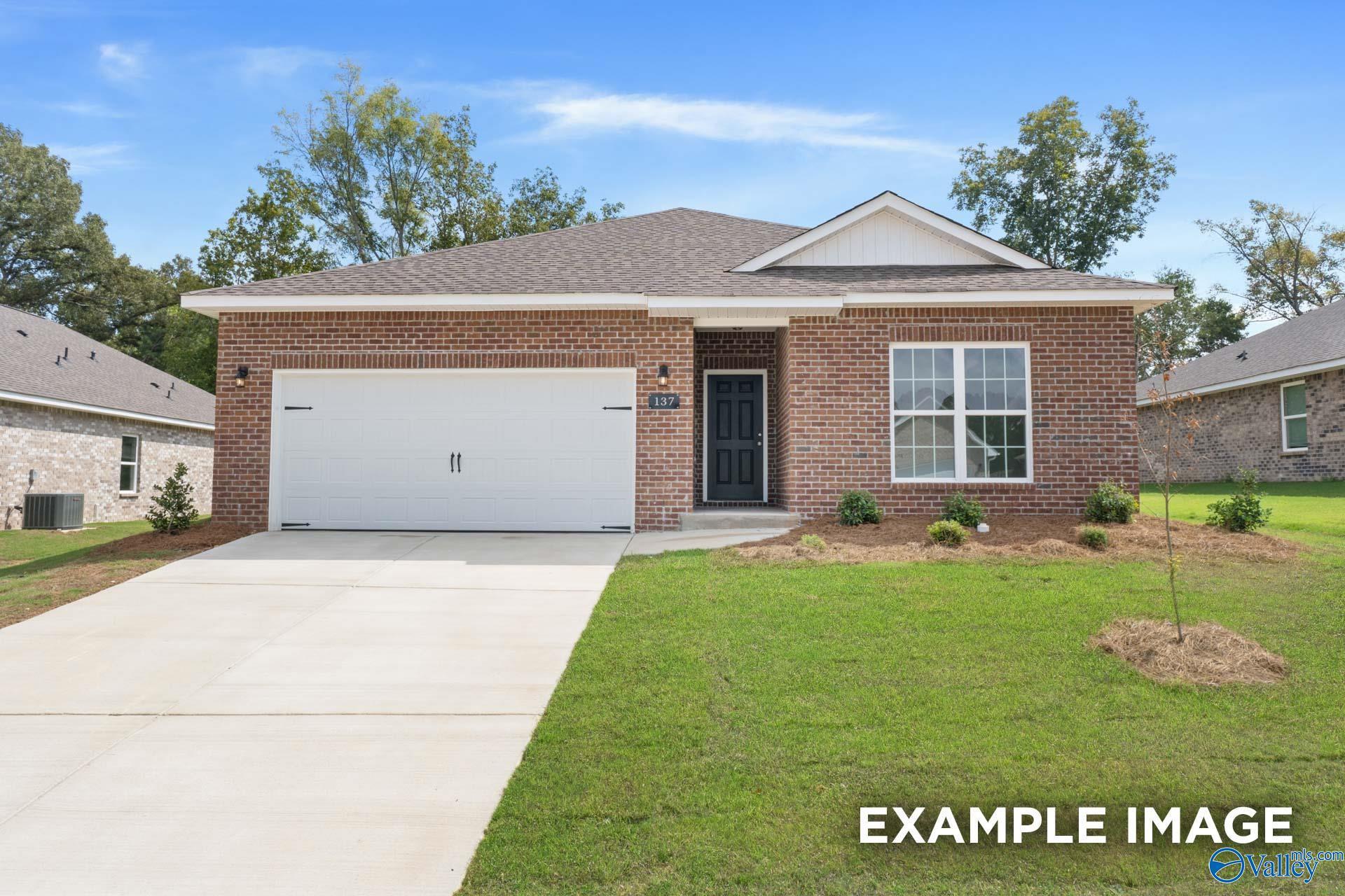 Modern single-story brick home with 2-car garage, driveway, and lush front yard in Jaguar Hills, Huntsville, Alabama