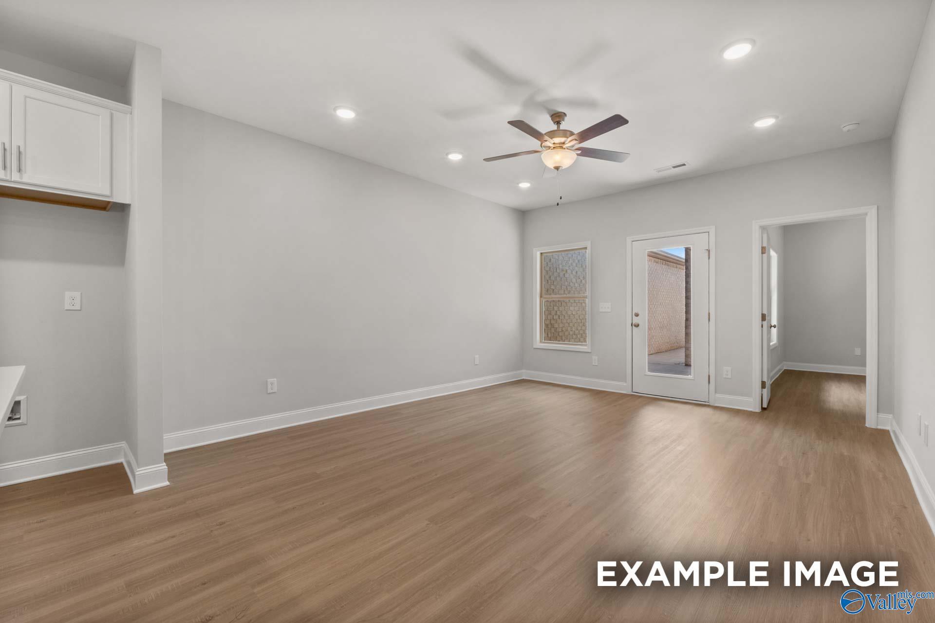 Spacious living room with hardwood floors, ceiling fan, French doors to patio, and gray walls in Davidson Homes The Camilla B, Hartselle, AL