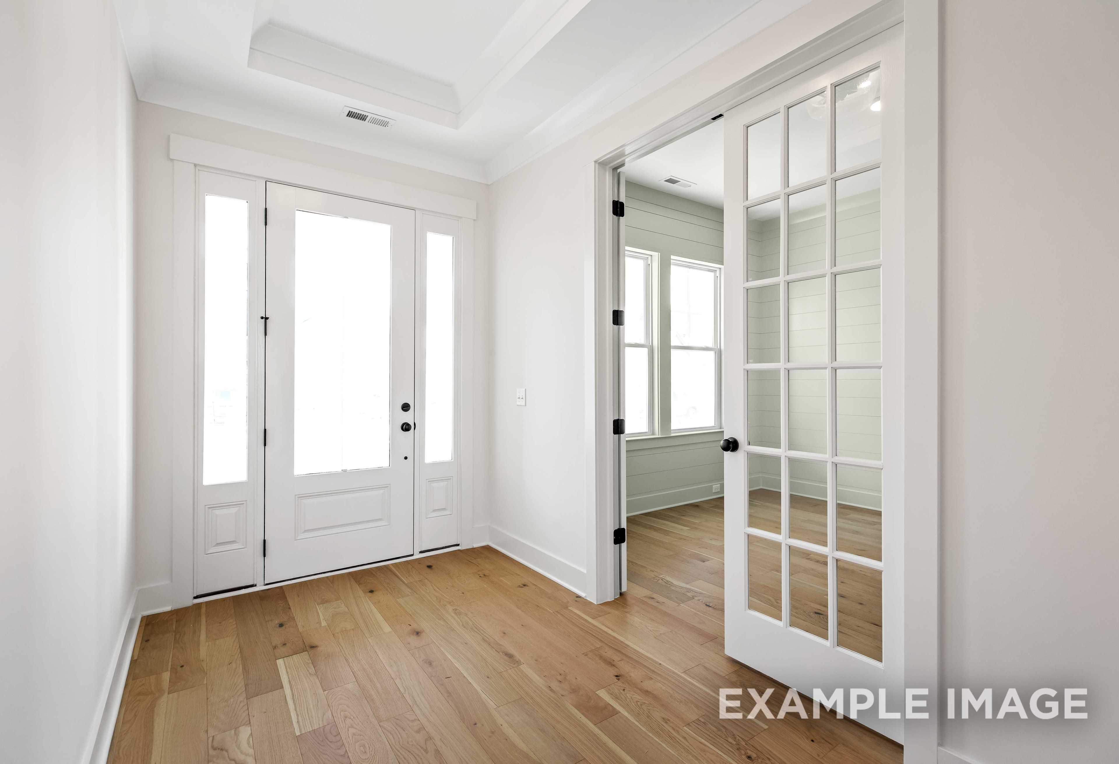 Bright entryway in The Albany A home by Davidson Homes featuring white glass-paneled doors, hardwood floors, and open archway
