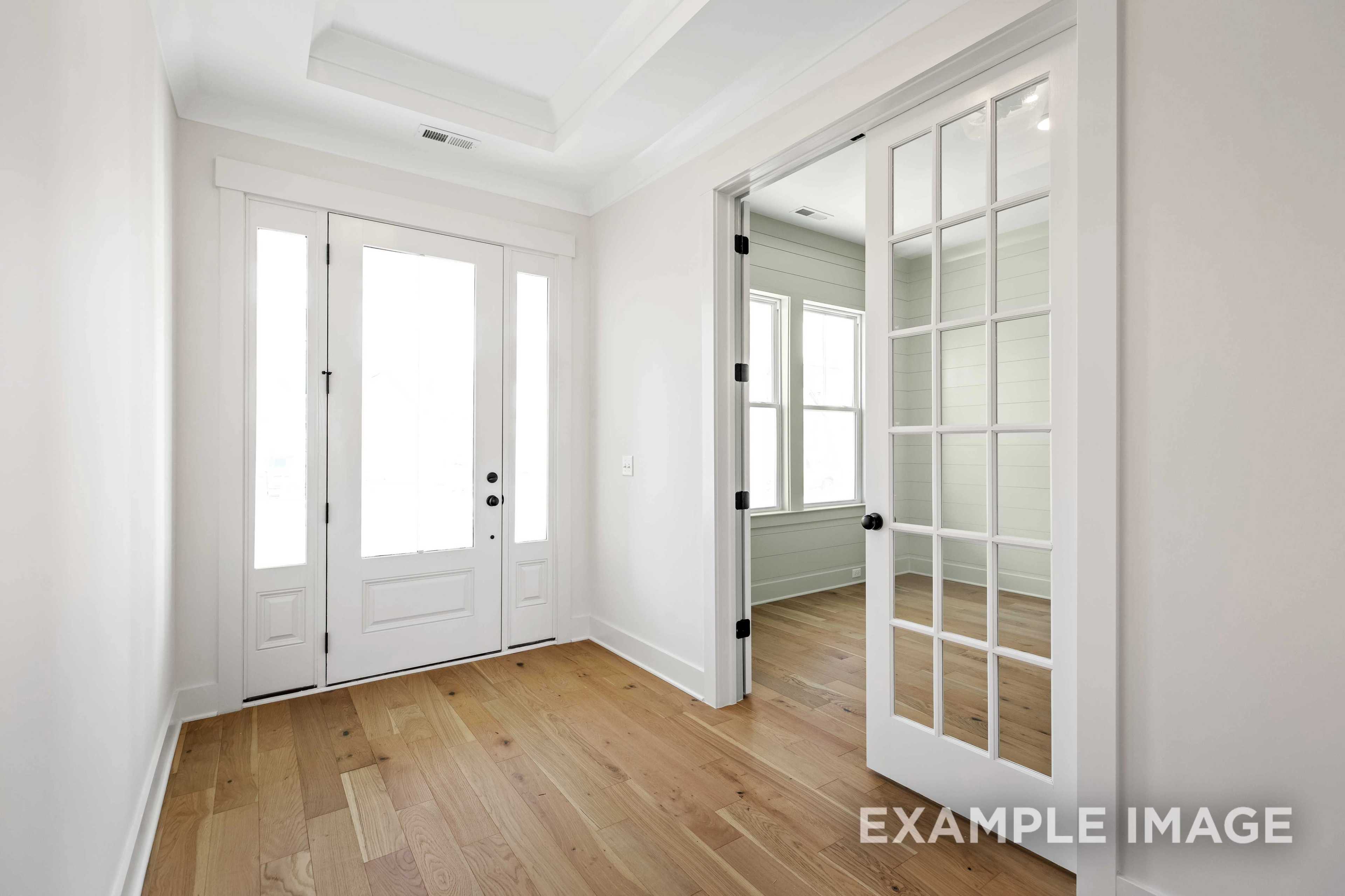 Bright entryway in The Albany A home by Davidson Homes featuring white glass-paneled doors, hardwood floors, and open archway