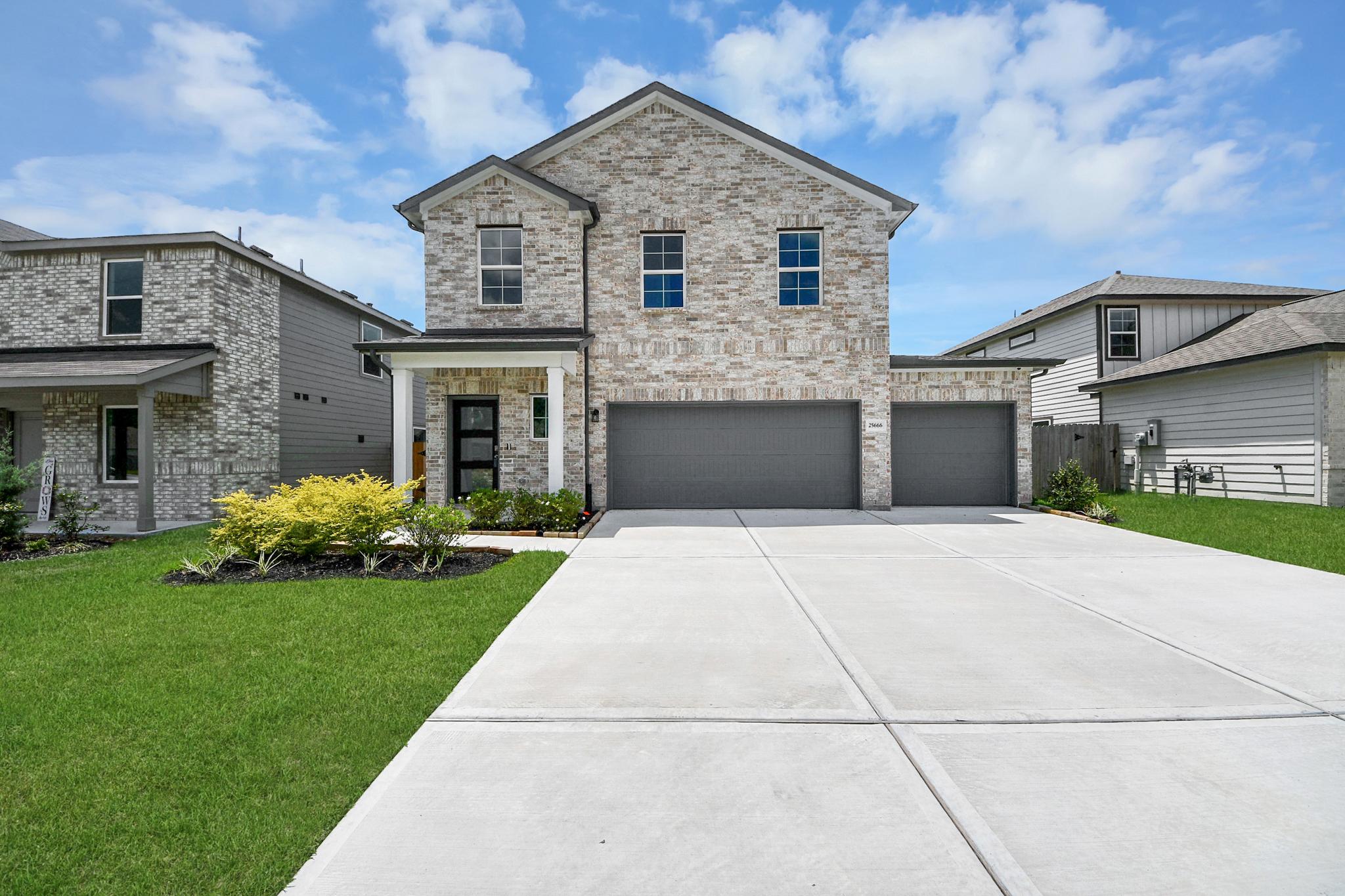 Two-story brick home exterior at Hill & Dale Ranch in Splendora, TX, featuring a three-car garage by Davidson Homes.