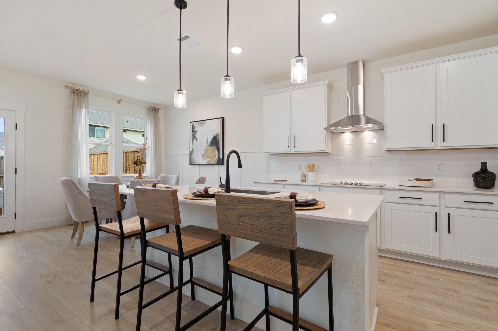 Spacious modern kitchen at Lake Park Villas in Wylie TX with white shaker cabinets, quartz island, wood bar stools, and open dining area
