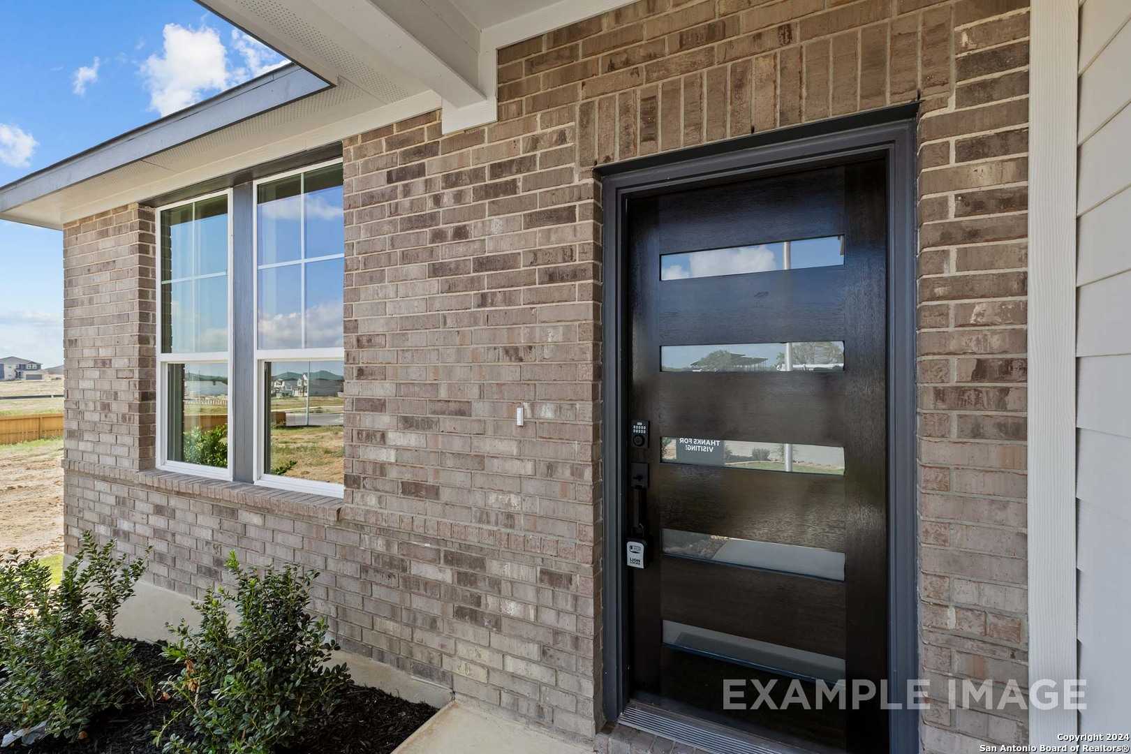 Modern brick exterior with black slatted door, large windows, and covered porch in Davidson Homes The Douglas G, Bricewood, San Antonio
