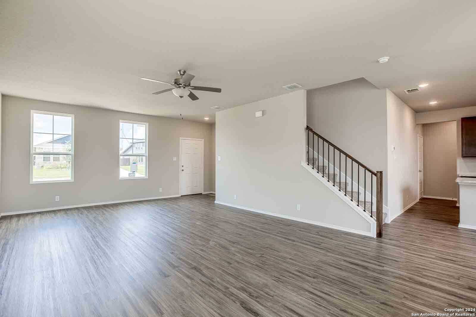 Spacious foyer with hardwood floors, ceiling fan, large windows, and staircase in Davidson Homes The Murray H, Seguin, Texas