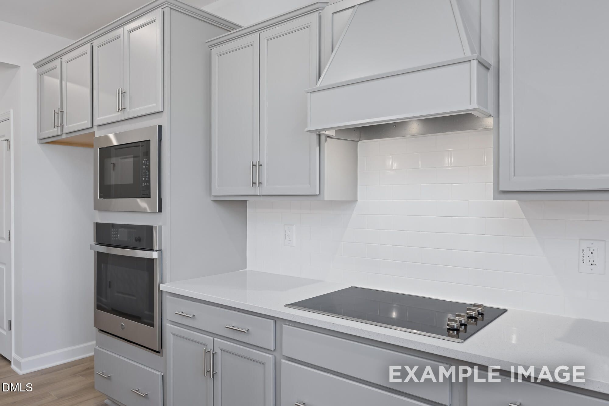 Modern white shaker kitchen with stainless double oven, induction cooktop, and subway tile backsplash in The Hickory II B, Lillington, NC