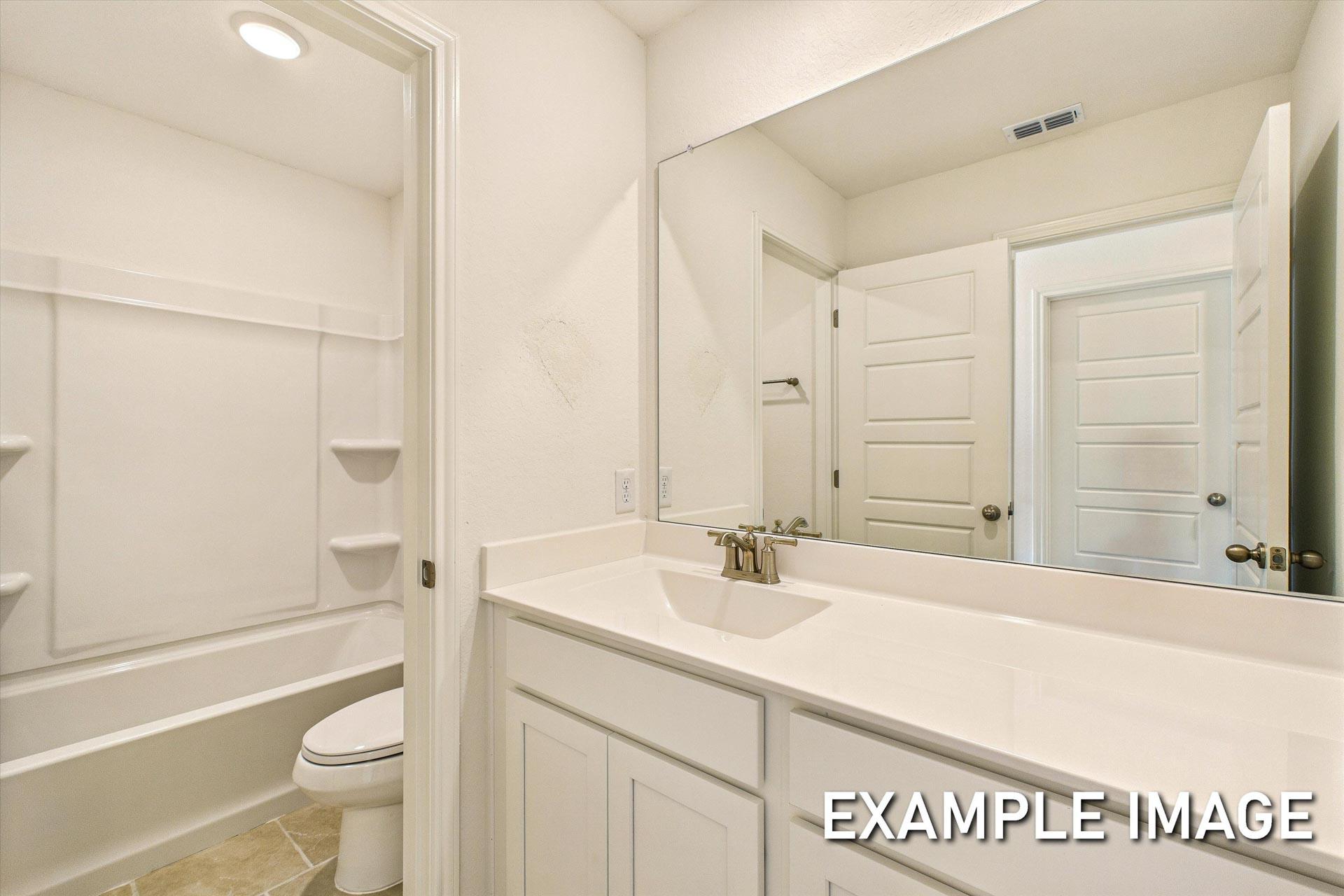 Spacious upstairs master bathroom in The Trinity B by Davidson Homes featuring white vanity, soaking tub, walk-in shower, and toilet