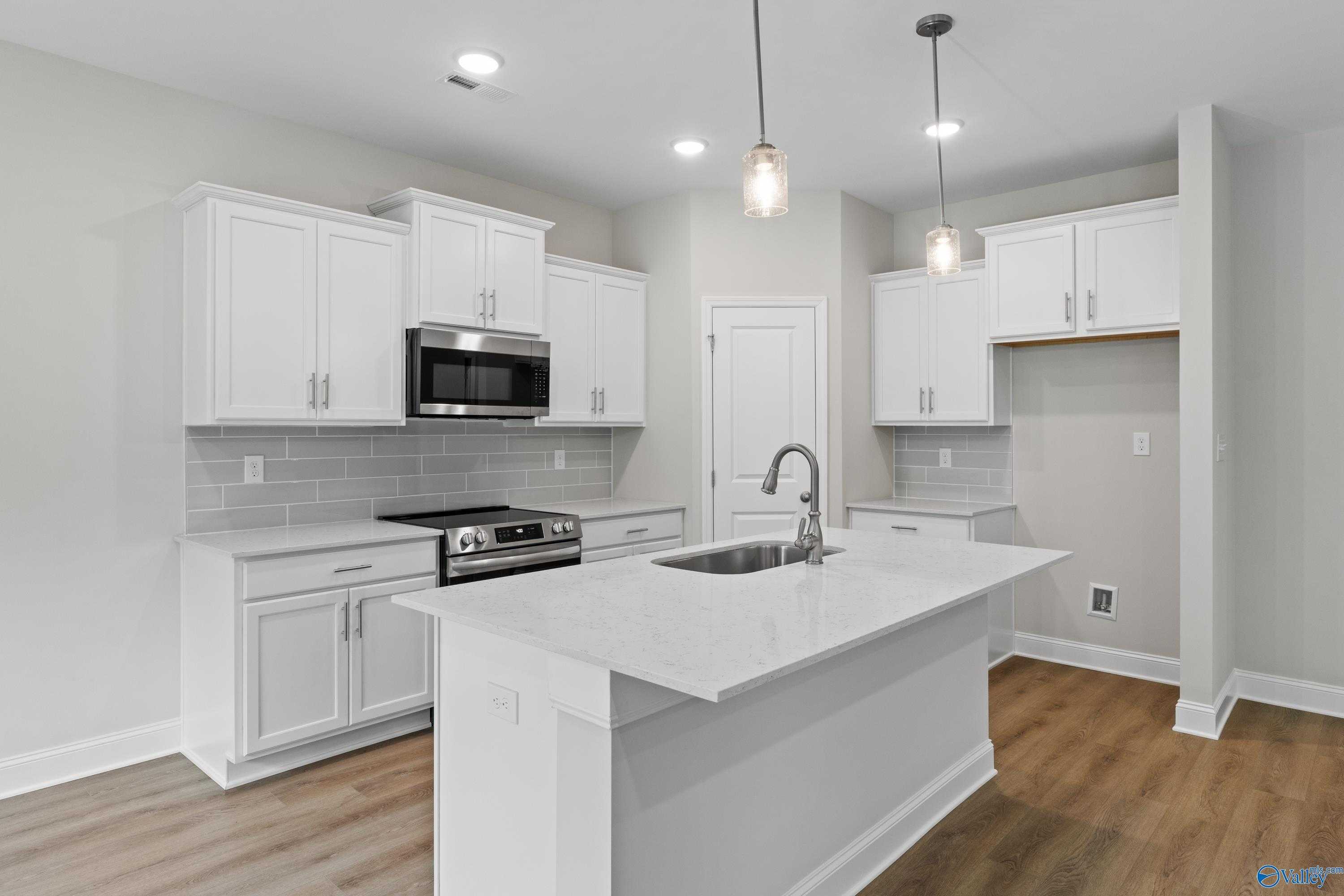 Modern white kitchen with quartz island, stainless appliances, subway tile backsplash in Davidson Homes The Asheville C, Huntsville AL
