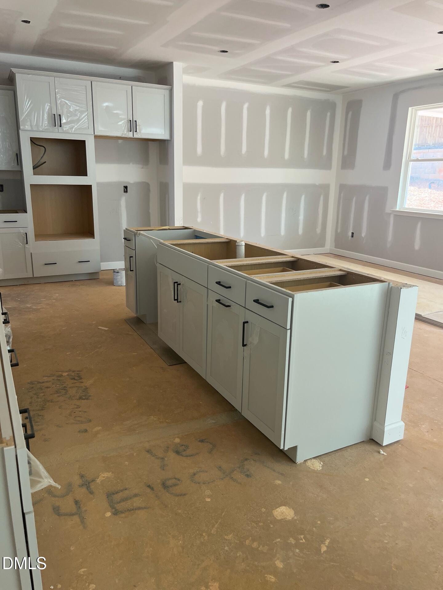 Unfinished open-concept kitchen with white shaker cabinets and island in Davidson Homes The Beech B, Wake Forest, NC