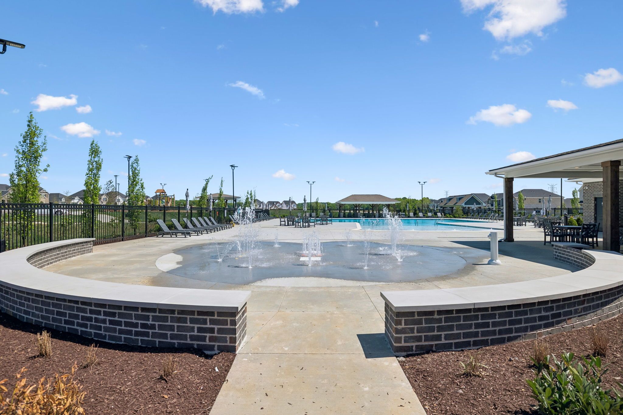 Splash pad and swimming pool at Bradshaw Farms in Mt. Juliet, Tennessee by Davidson Homes with lounge seating.