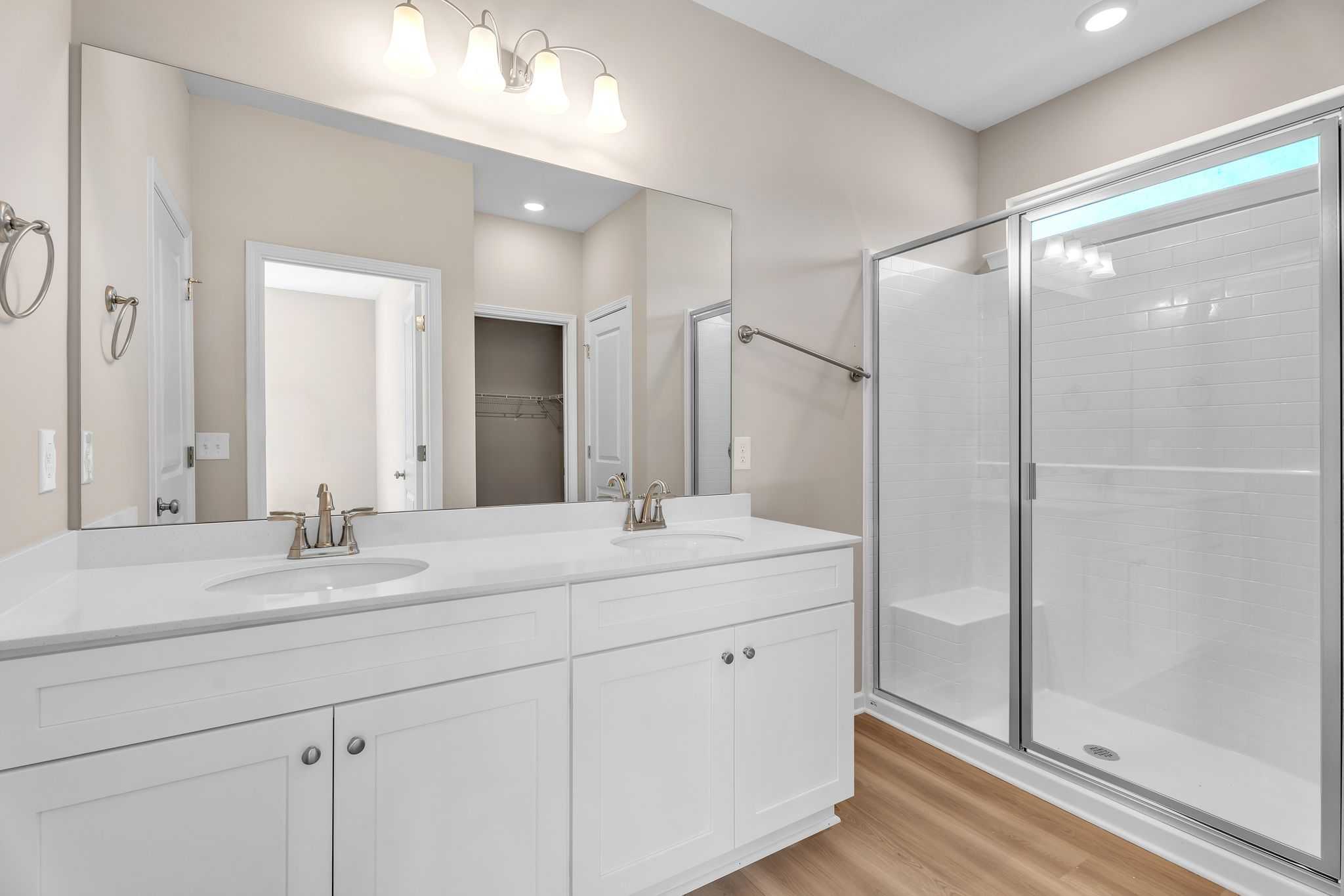 Spacious master bathroom at Anderson Lakes in Opelika Alabama with double vanity, walk-in shower, and hardwood floors