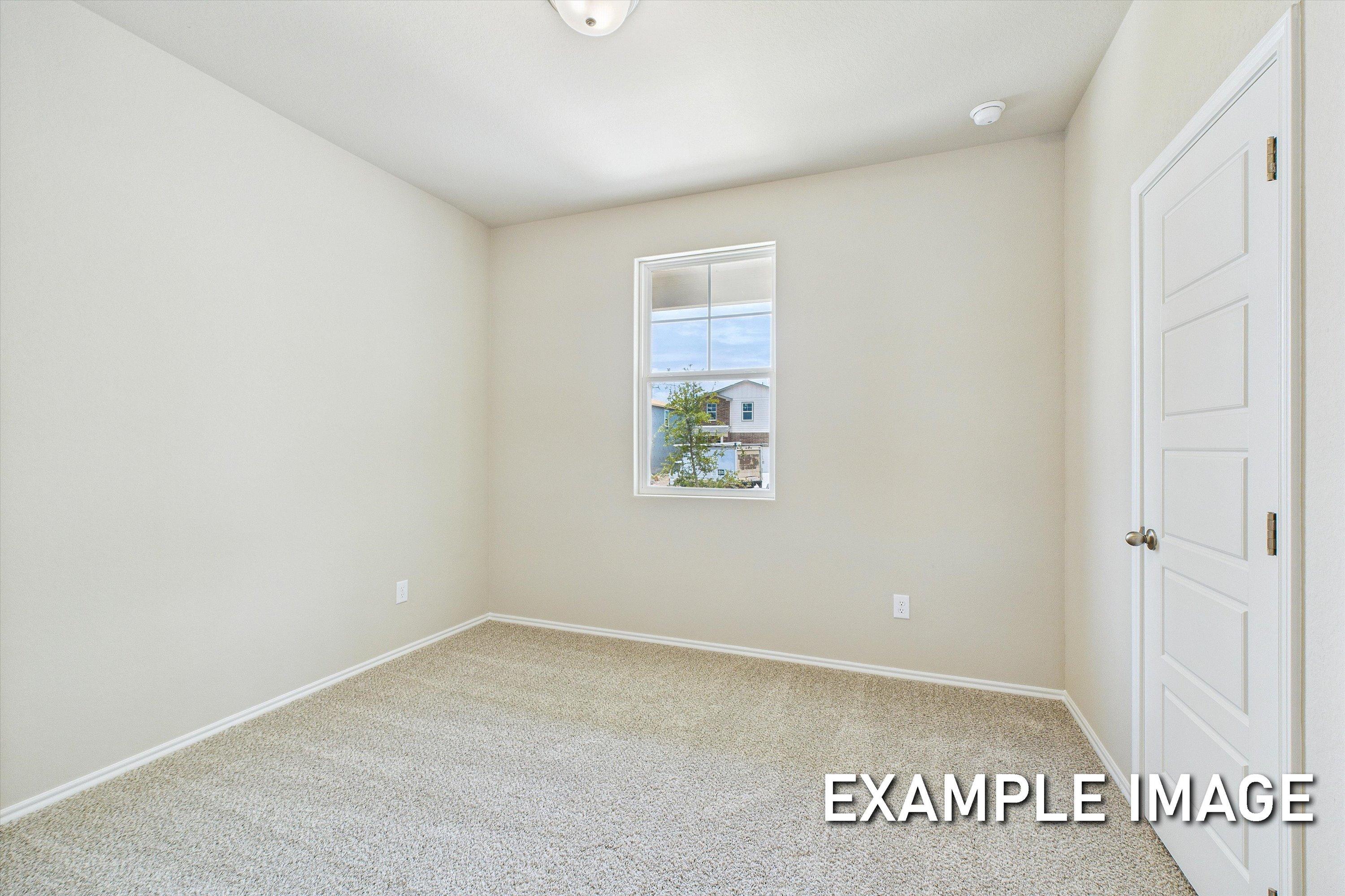 Spacious secondary bedroom in The Comal A floor plan featuring neutral paint, plush carpeting, and a bright window.