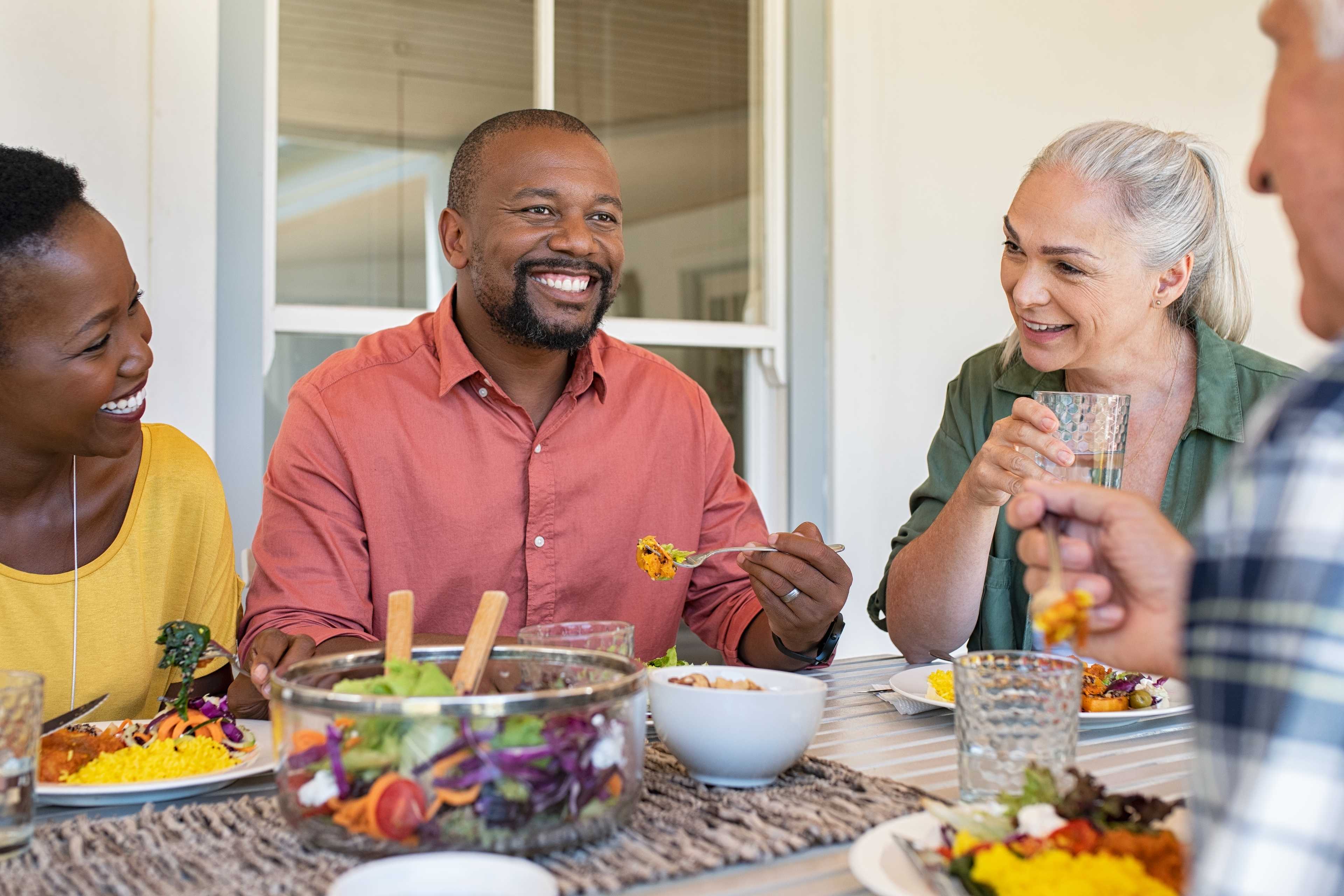 Diverse adults smiling over fresh salads and drinks on covered porch at Kelly Preserve in Loganville, Georgia