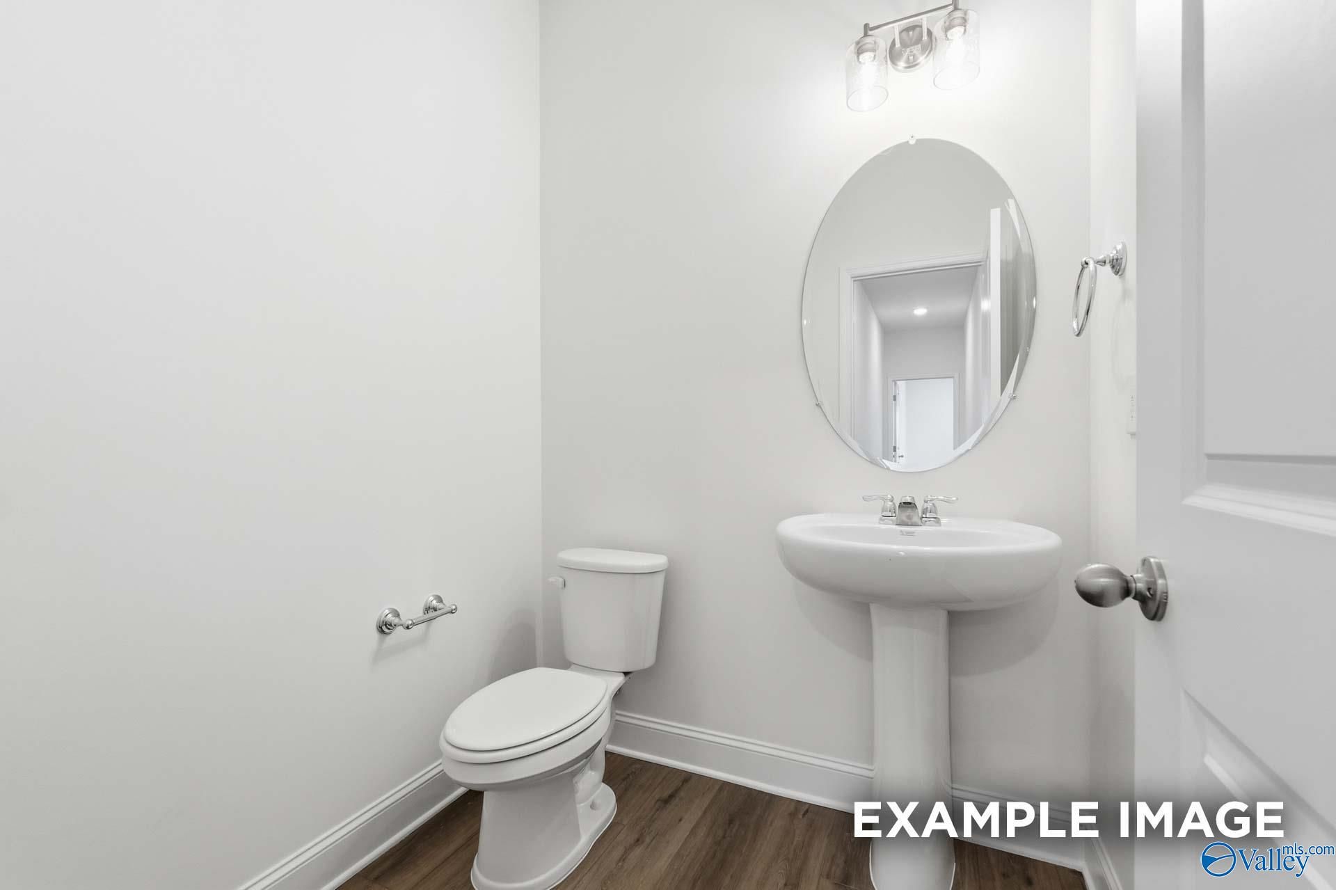 Modern half-bath with pedestal sink and oval mirror in The Valencia floor plan by Davidson Homes in Meridianville, Alabama.