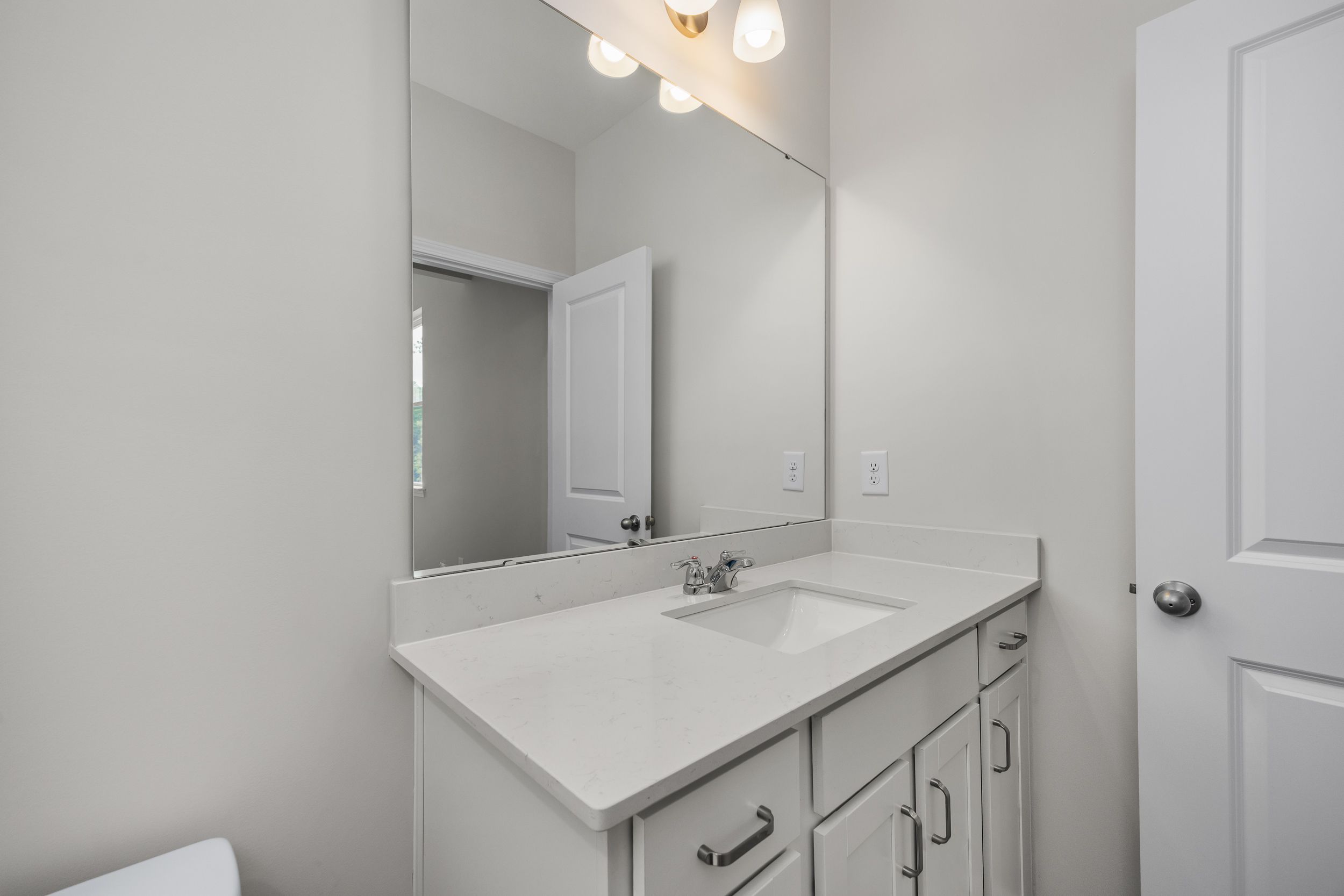 Modern master bathroom vanity in The Aspen by Davidson Homes with white quartz countertop, undermount sink, and mirrored wall
