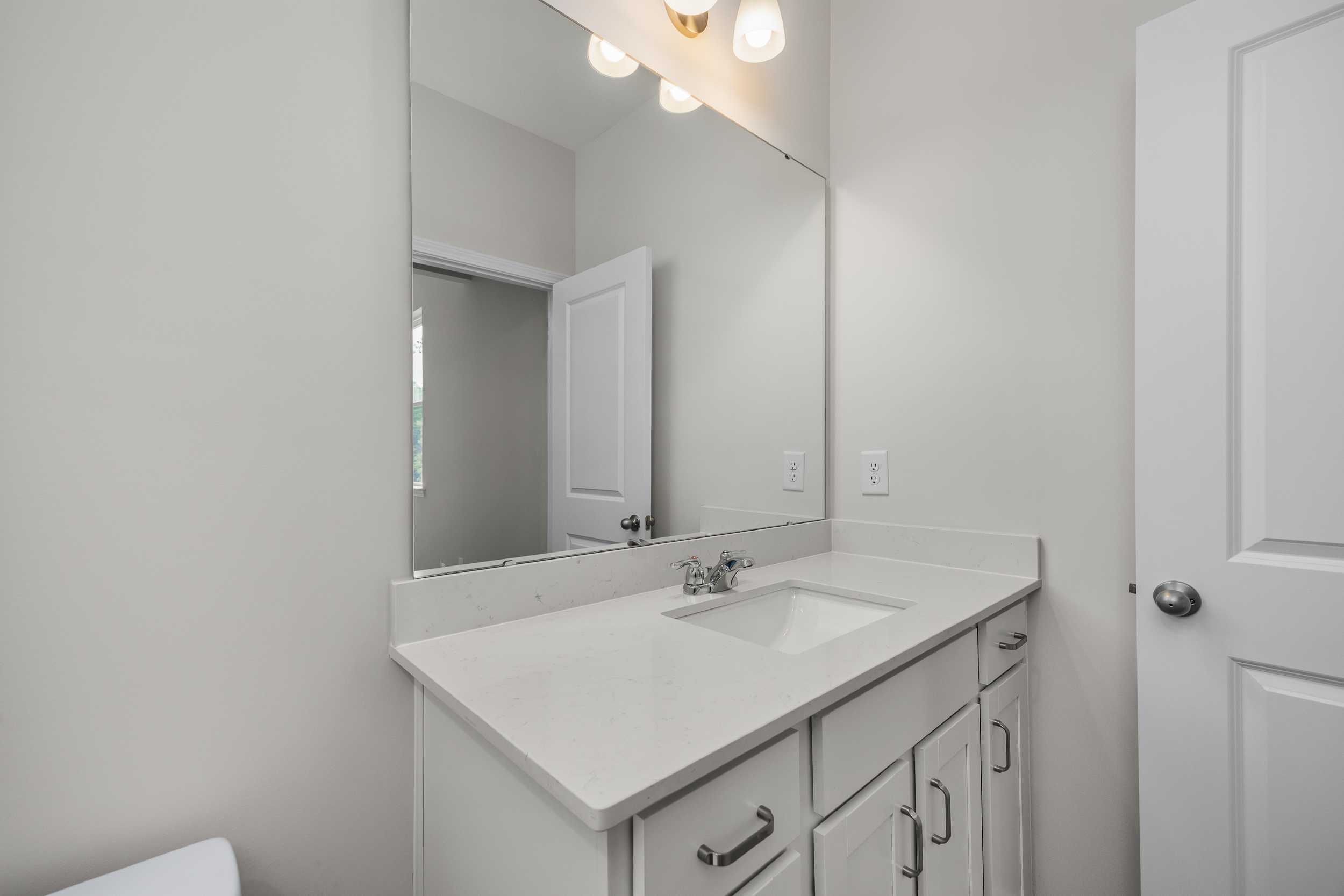 Modern master bathroom vanity in The Aspen by Davidson Homes with white quartz countertop, undermount sink, and mirrored wall