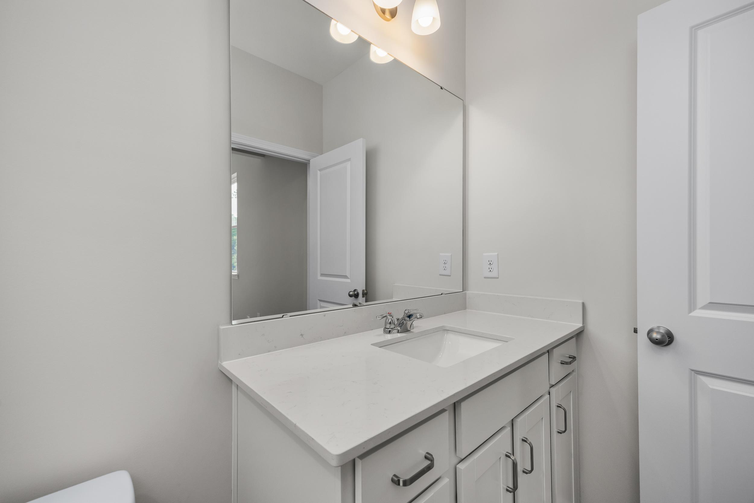 Modern master bathroom vanity in The Aspen by Davidson Homes with white quartz countertop, undermount sink, and mirrored wall