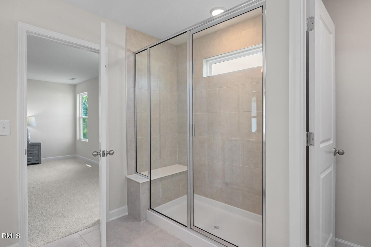Elegant master bathroom with frameless glass walk-in shower, subway tile walls, and built-in bench in Davidson Homes The Preston A, Lillington, NC