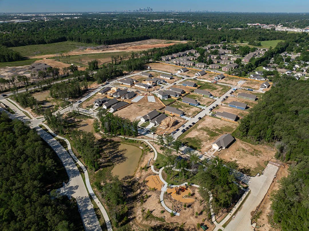 Aerial view of Robins Landing Houston TX neighborhood by Davidson Homes featuring new homes under construction, wooded trails, and playground