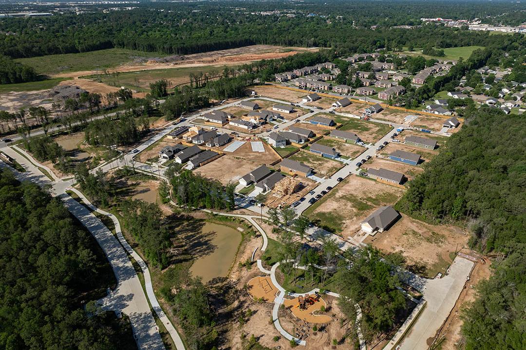 Aerial view of Robins Landing Houston TX neighborhood by Davidson Homes featuring new homes under construction, wooded trails, and playground