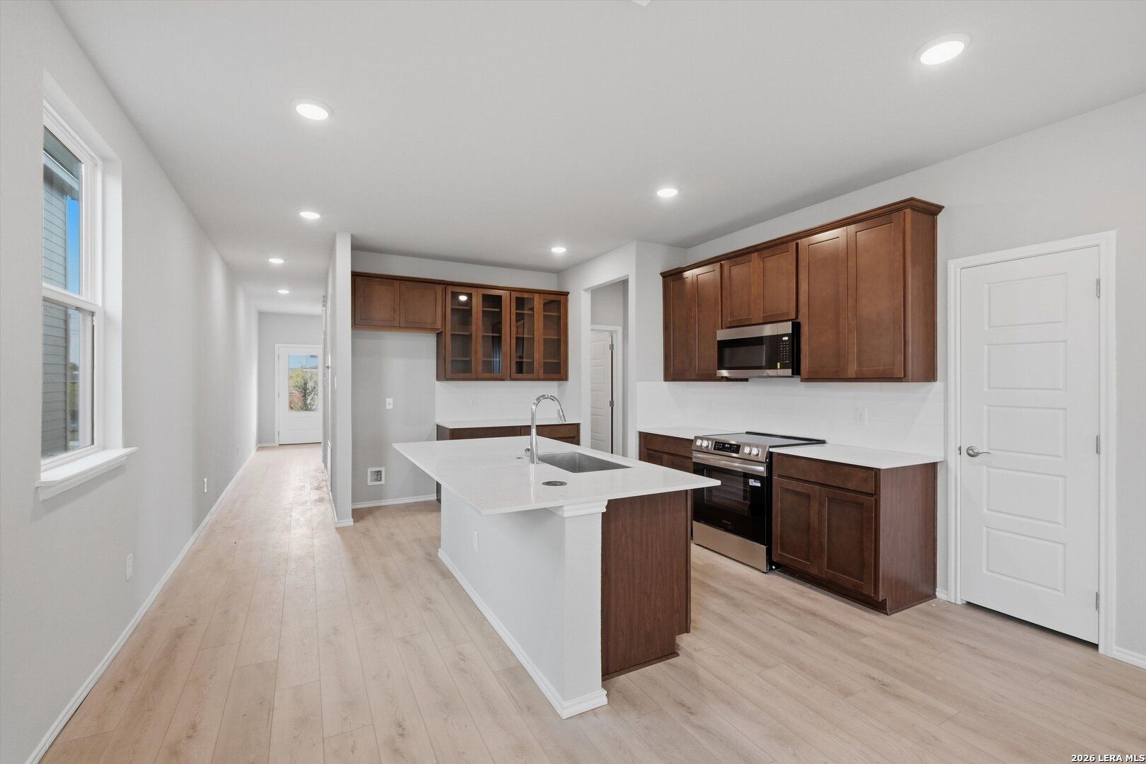 Modern open-concept kitchen with white quartz island, shaker cabinets, stainless appliances in The Frio B, Agave San Antonio