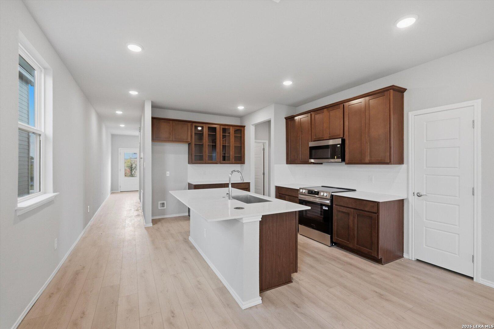 Modern open-concept kitchen with white quartz island, shaker cabinets, stainless appliances in The Frio B, Agave San Antonio
