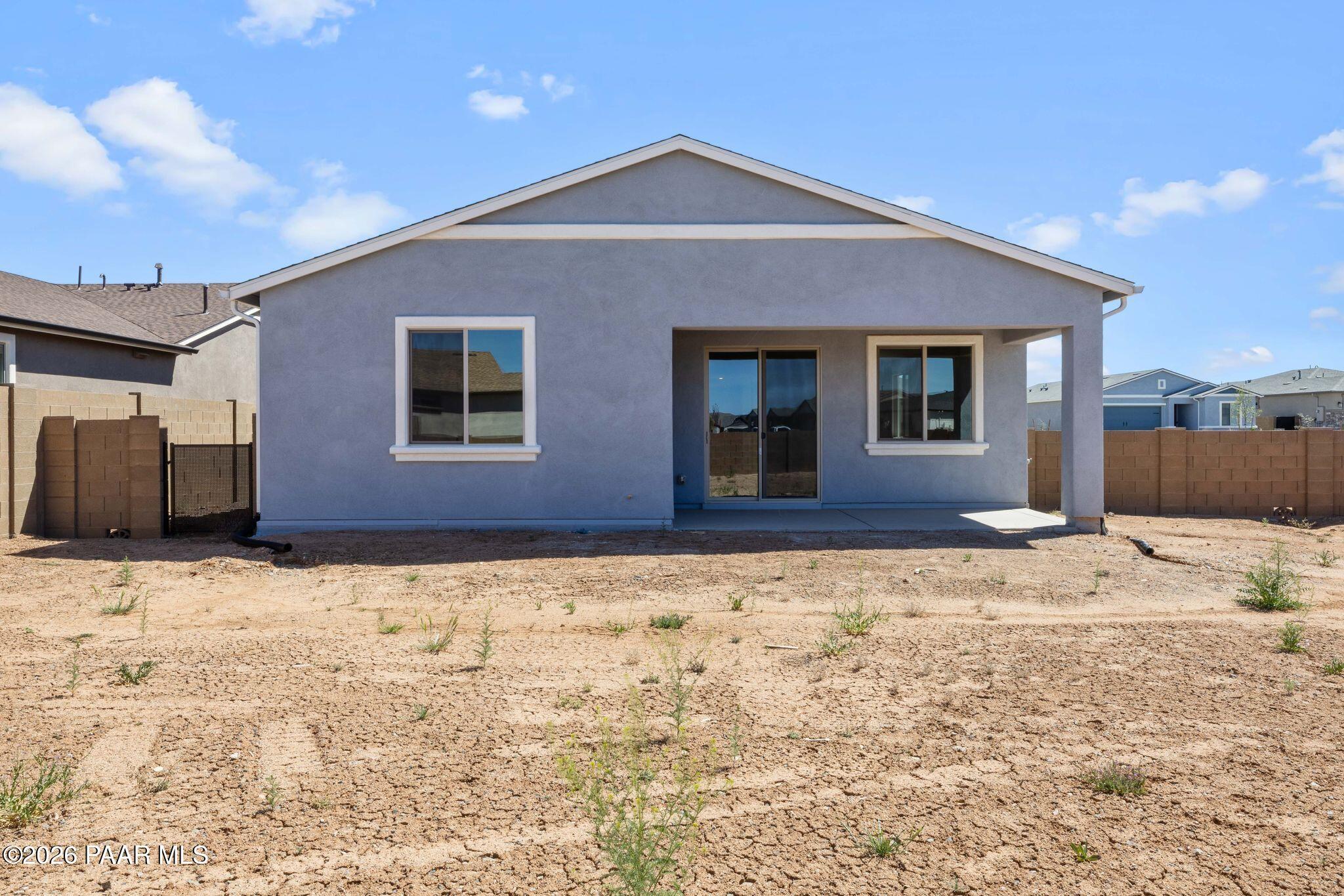 Back view of light blue single-story The Frontier A home with covered patio, sliding doors, and desert yard in North Ridge at Pronghorn Ranch, Prescott Valley, Arizona
