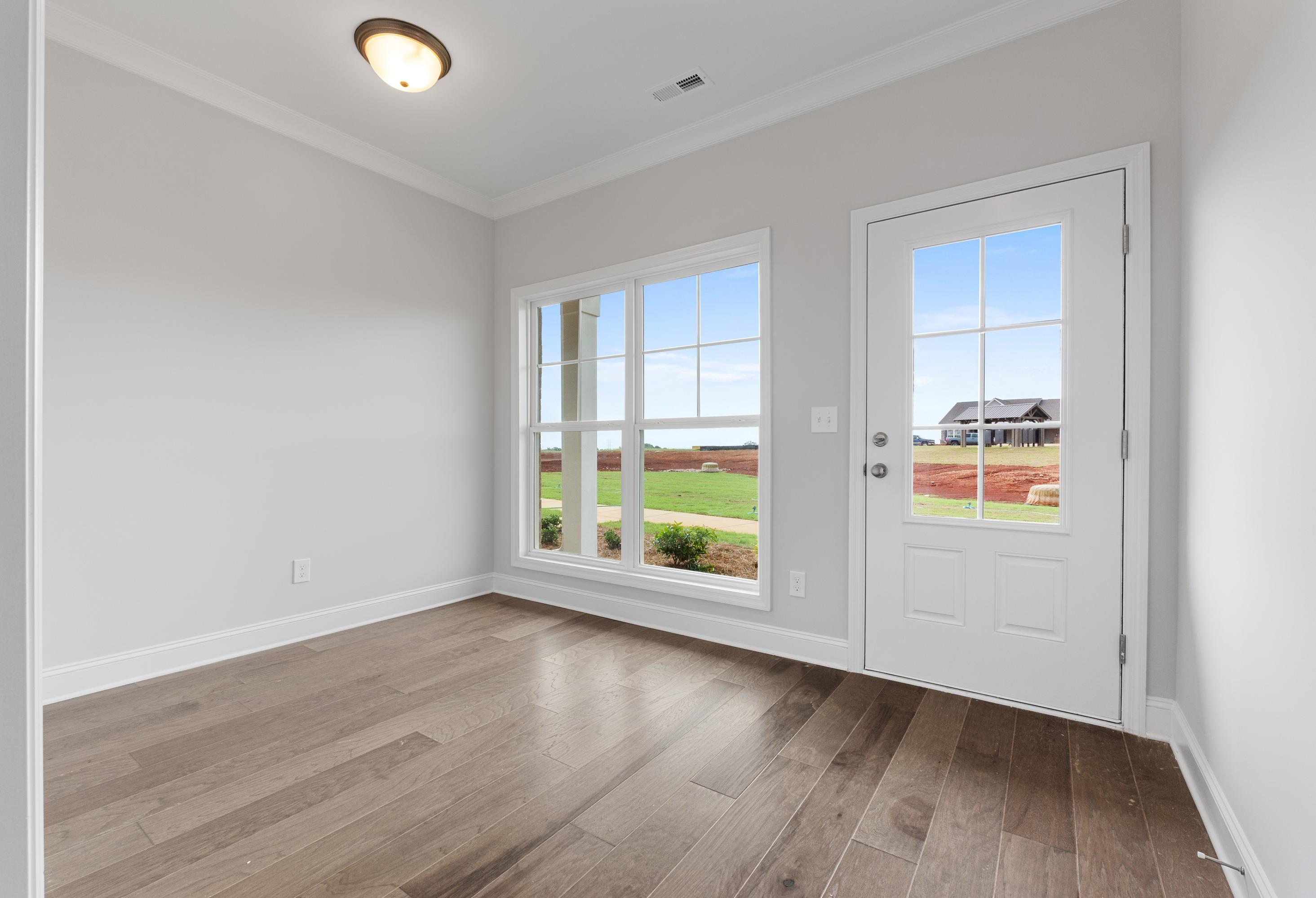 Empty bedroom in The Copeland B showcasing light gray walls, hardwood floors, large windows with yard view, Davidson Homes design