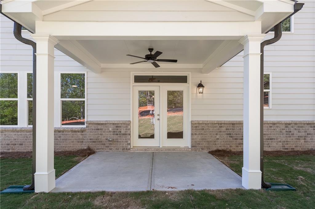 Covered patio with white columns, black ceiling fan, and glass French doors in Davidson Homes The Hickory E, Buford, GA